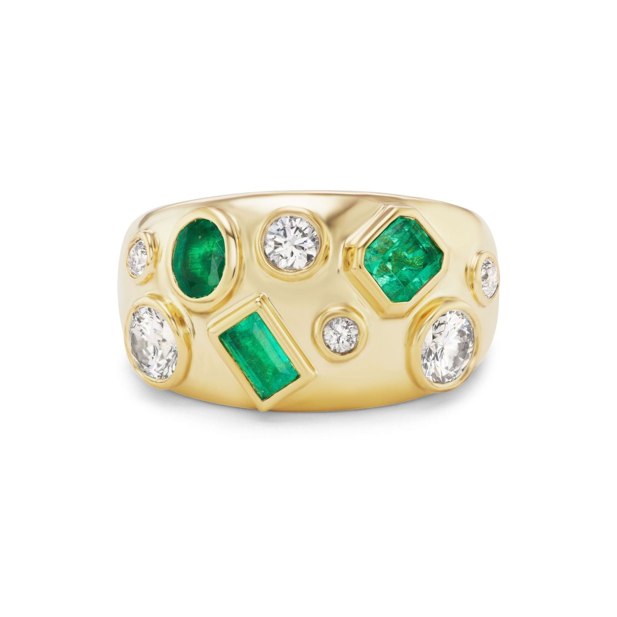 The Bezel Set Cigar Band in Yellow Gold features an array of mixed shape white diamonds and green emeralds in various sizes, arranged in an asymmetric, scattered pattern across the wide band.
