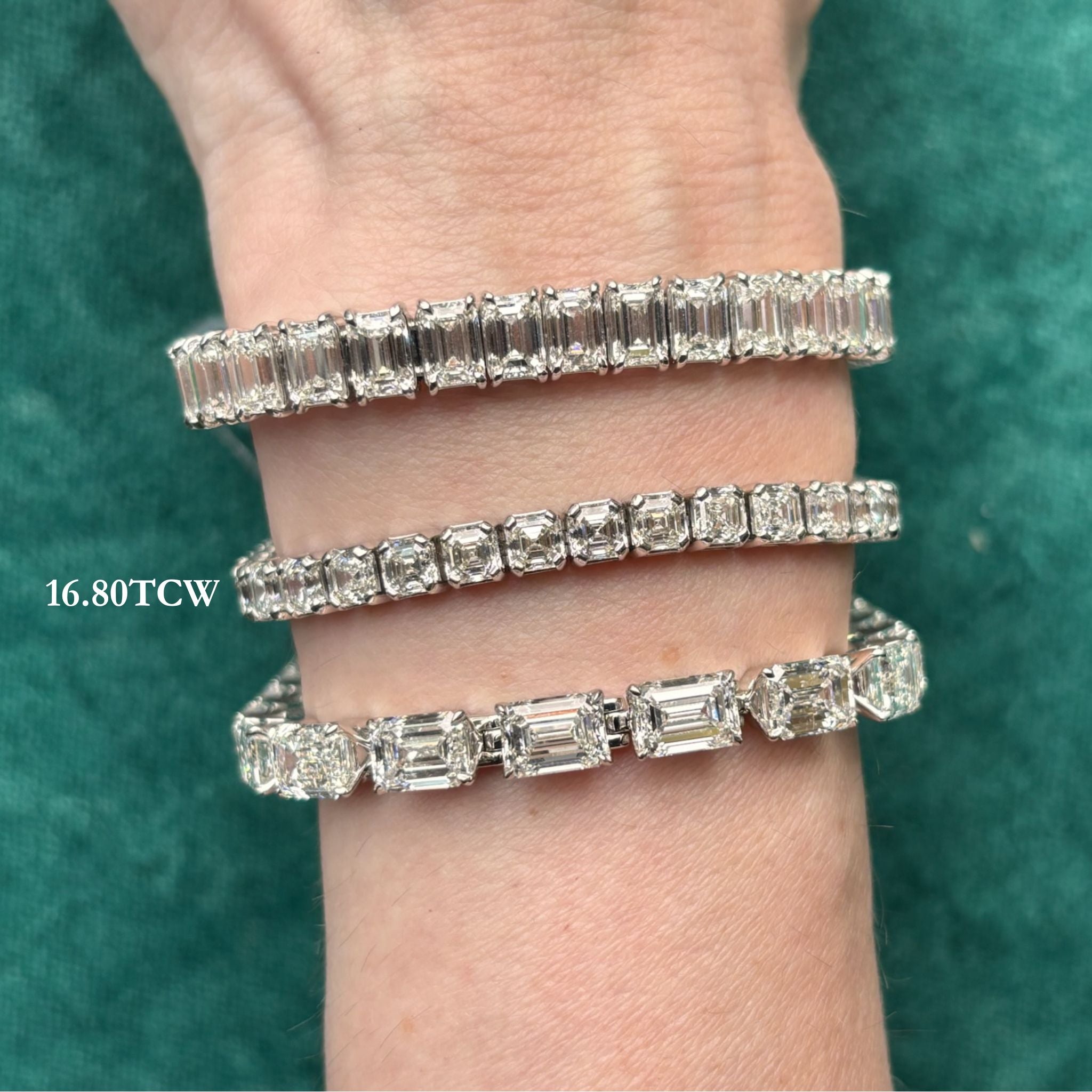 A hand wears three Asscher cut diamond tennis bracelets with varying cuts and sizes, including Asscher cut diamonds of VVS-VS clarity, on a green fabric background. White text reads "16.80 TCW" near the bracelets—all set in luminous 18k white gold. Product shown: Tab Set Asscher Cut Diamond Tennis Bracelet in White Gold.