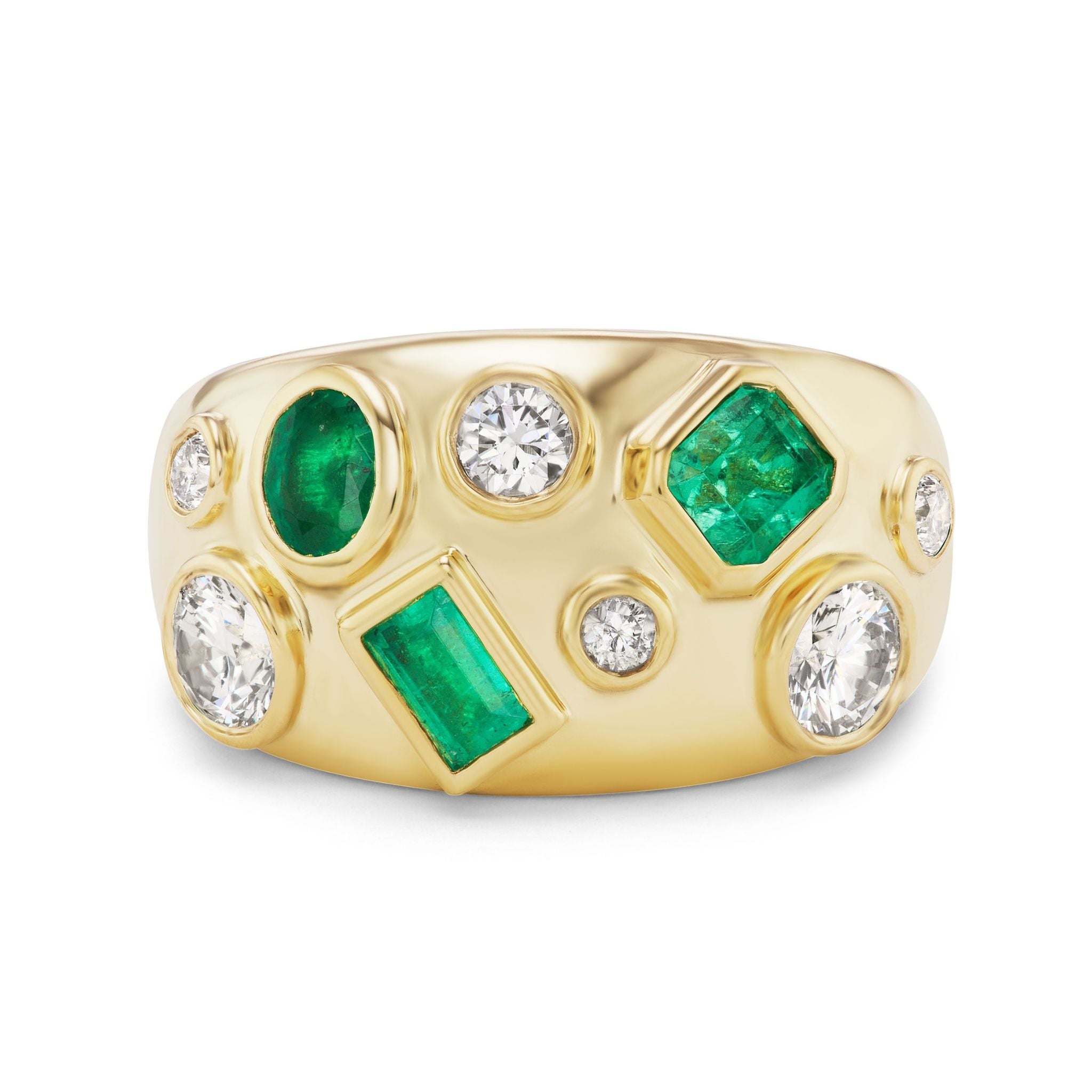 The Bezel Set Cigar Band in Yellow Gold features mixed shape diamonds and green emeralds in a scattered, modern cluster design across the wide band.