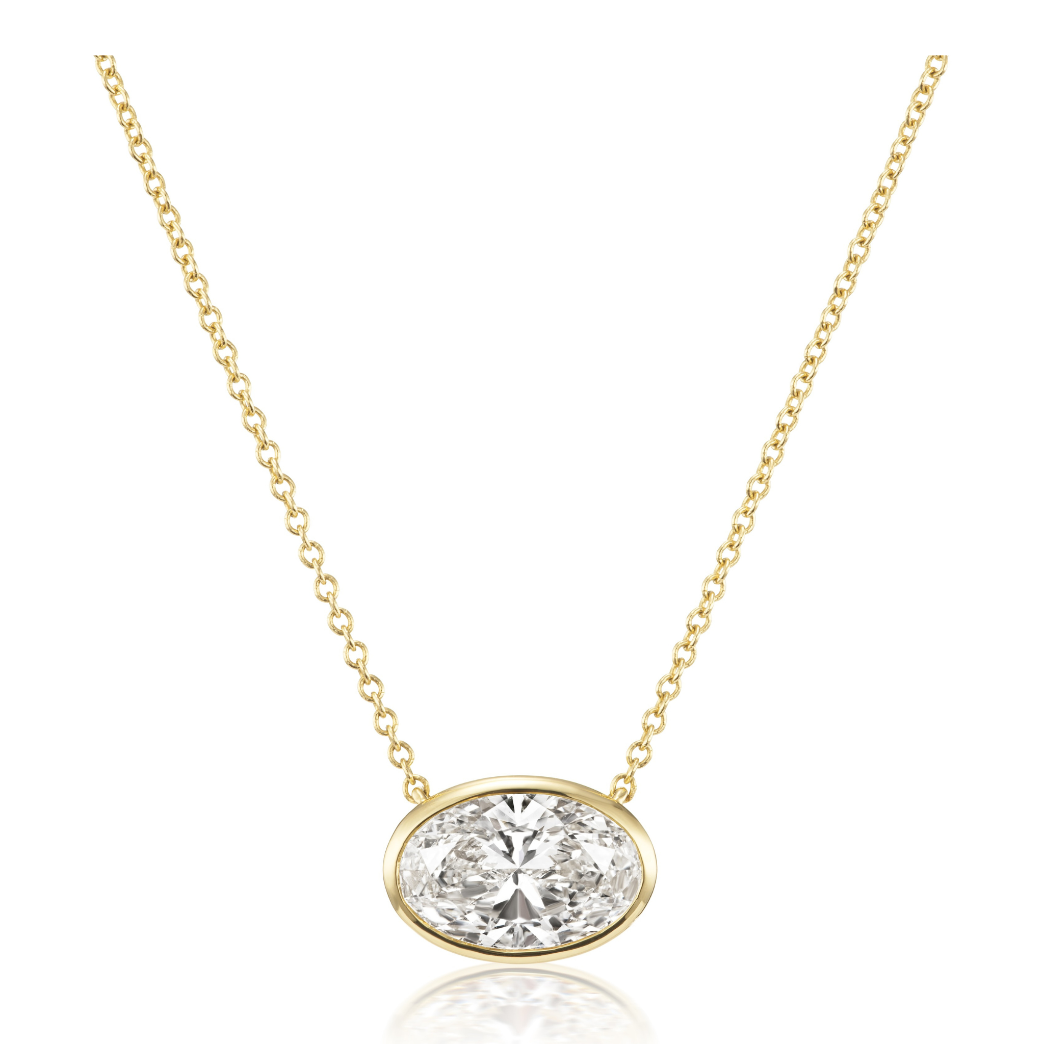 The East-West Bezel Set Oval Shape Diamond Pendant Necklace in Yellow Gold features an oval diamond bezel set on a delicate 18k yellow gold chain, creating an elegant centerpiece.