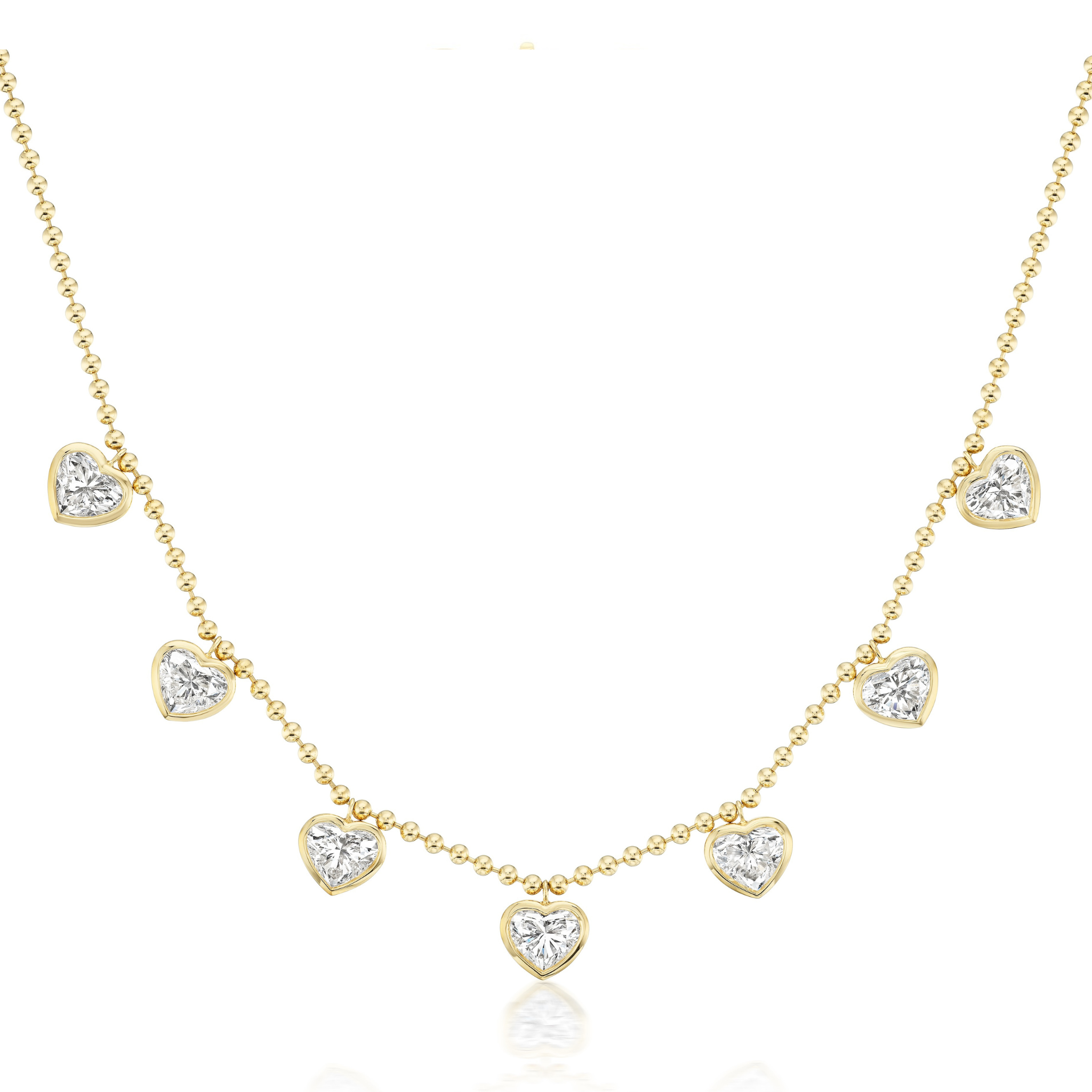 The Bezel Set Heart Shape Diamond Station Necklace features seven heart-shaped diamonds on a delicate 18k yellow gold ball chain.