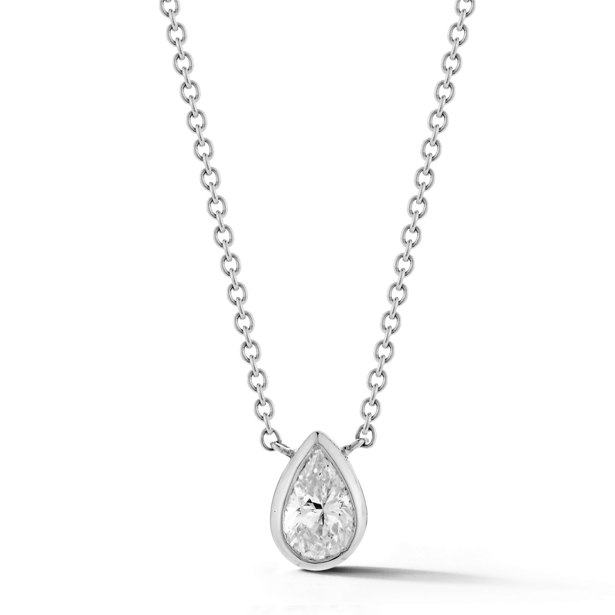 The Bezel Set Pear Diamond Solitaire Pendant in White Gold features a clear pear diamond in a simple bezel setting, hanging centrally from a fine white gold chain and elegantly showcased against a white background.