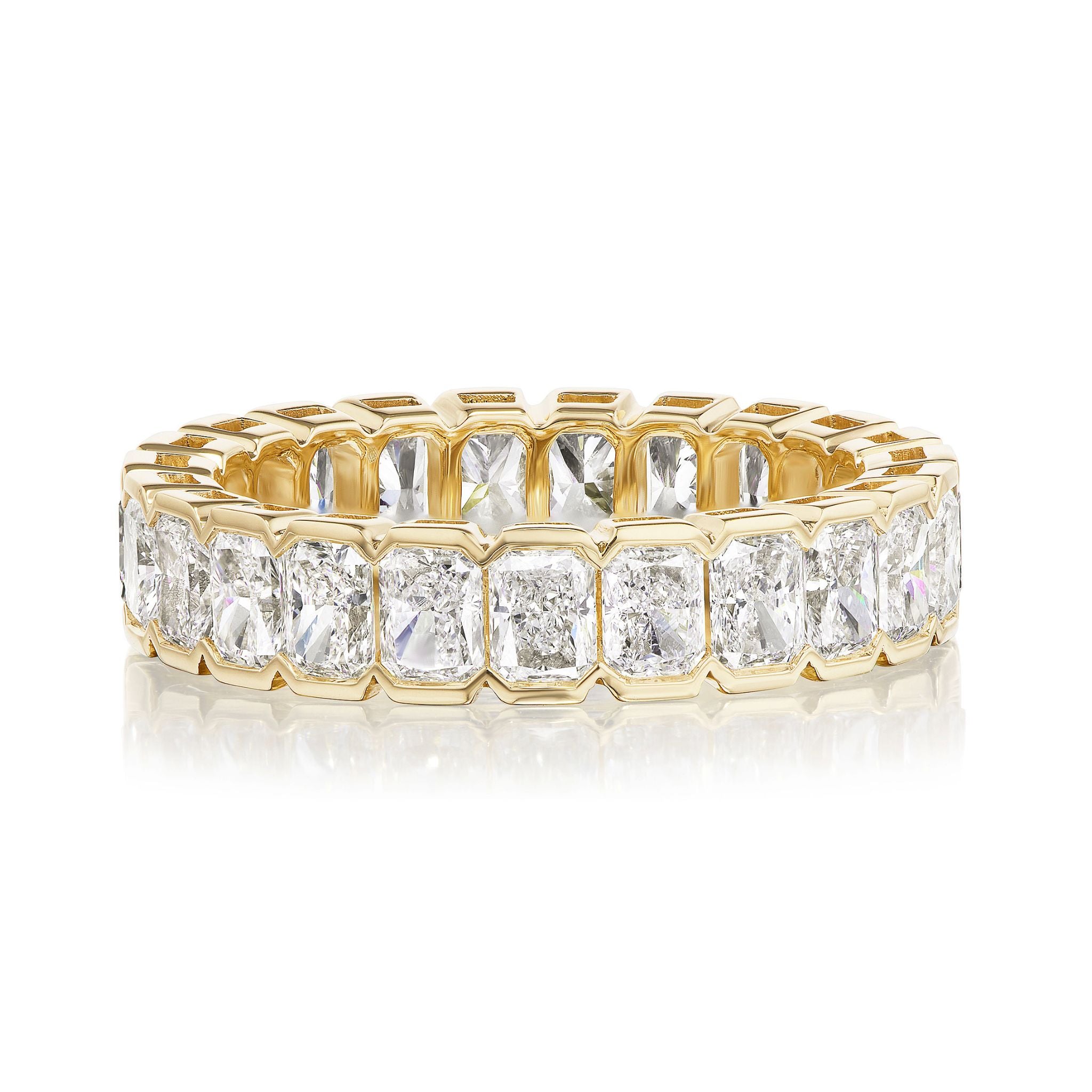 The Bracket Bezel Radiant Cut Diamond Eternity Band features radiant-cut diamonds in bezel settings, forming a continuous gold bridal band, shown on a white background.