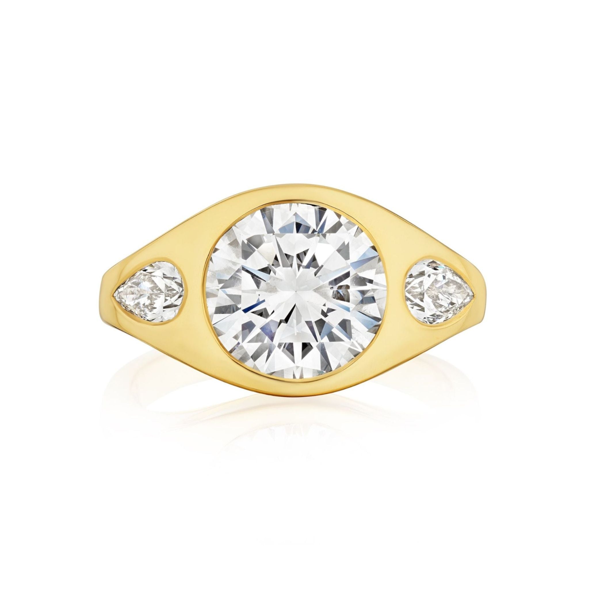 A Burnish Set Gypsy Ring with Round and Pear Shape Diamonds in Yellow Gold is displayed on a white background, featuring a yellow gold band adorned with a large round center diamond and two pear-shaped diamonds.