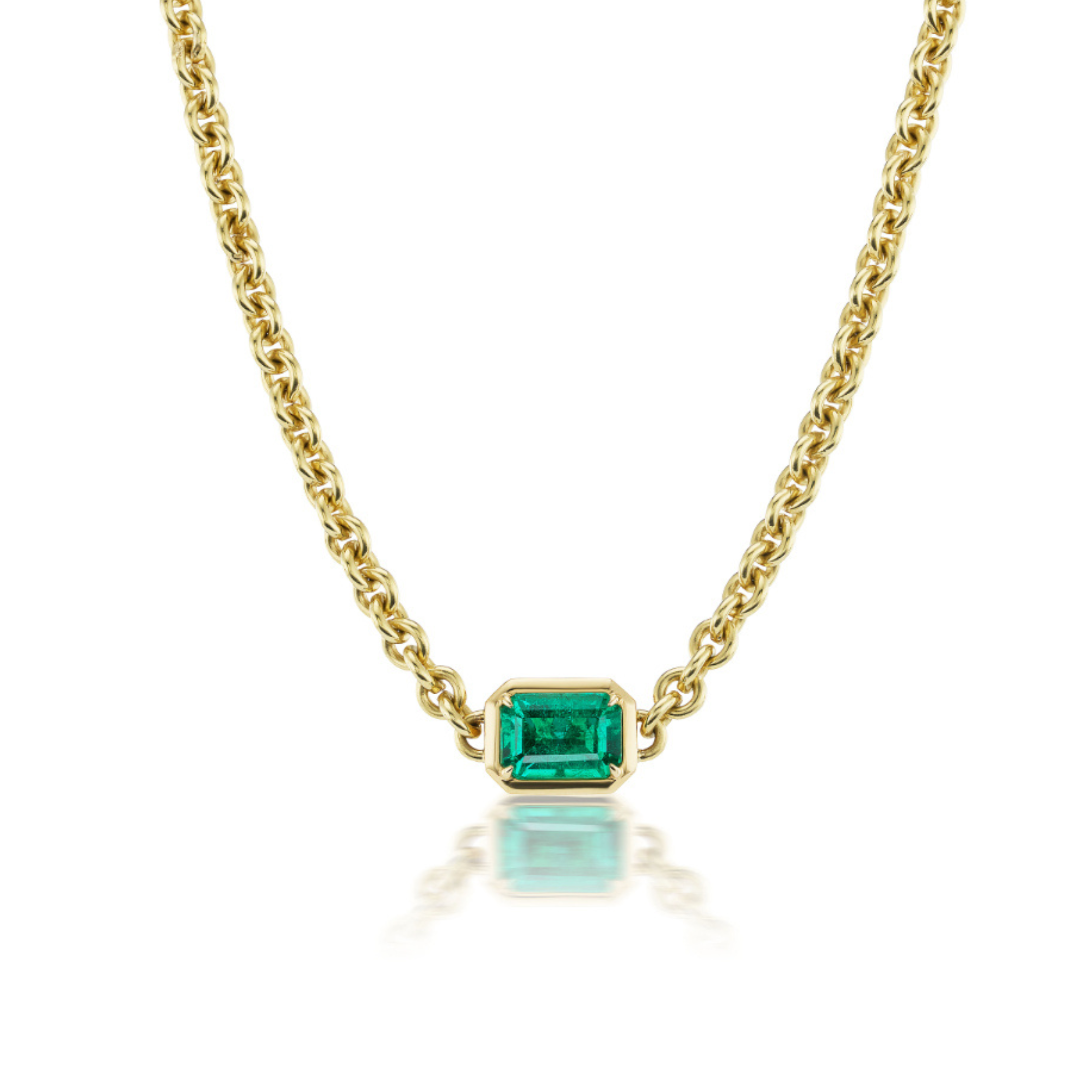 Chain Necklace in Yellow Gold with an emerald cut emerald, showcased on a white background with subtle reflection, features a bold gold chain and a rectangular bezel setting for the green gemstone.