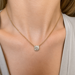 A close-up of a woman's neck wearing the Mosaic Pendant Necklace with an Asscher Cut Diamond on a yellow gold chain, styled with a light V-neck top.