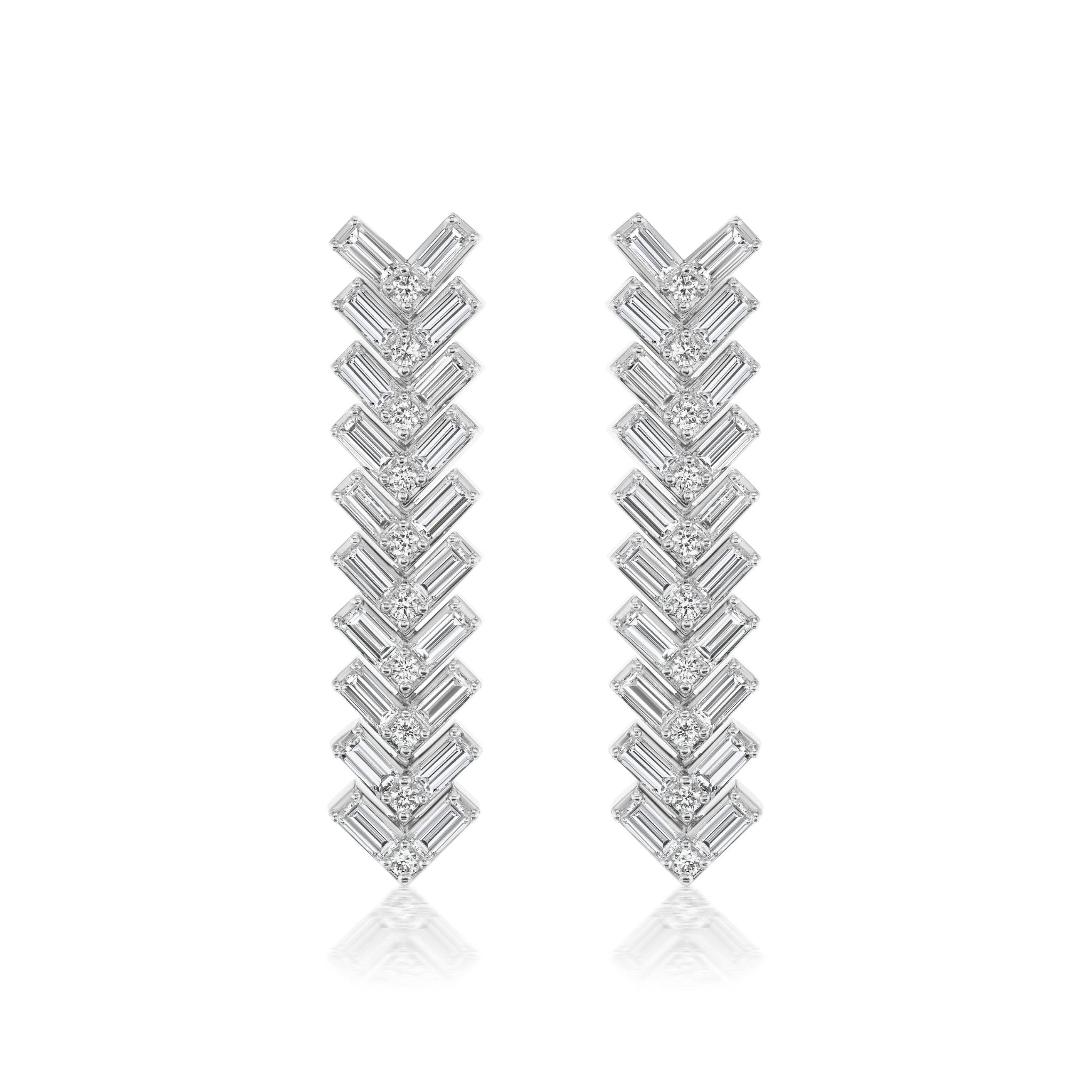 Elegant Chevron Drop Earrings in 18k white gold feature a vertical row of chevron-shaped segments adorned with round and baguette diamonds, creating a sparkling, symmetrical design.
