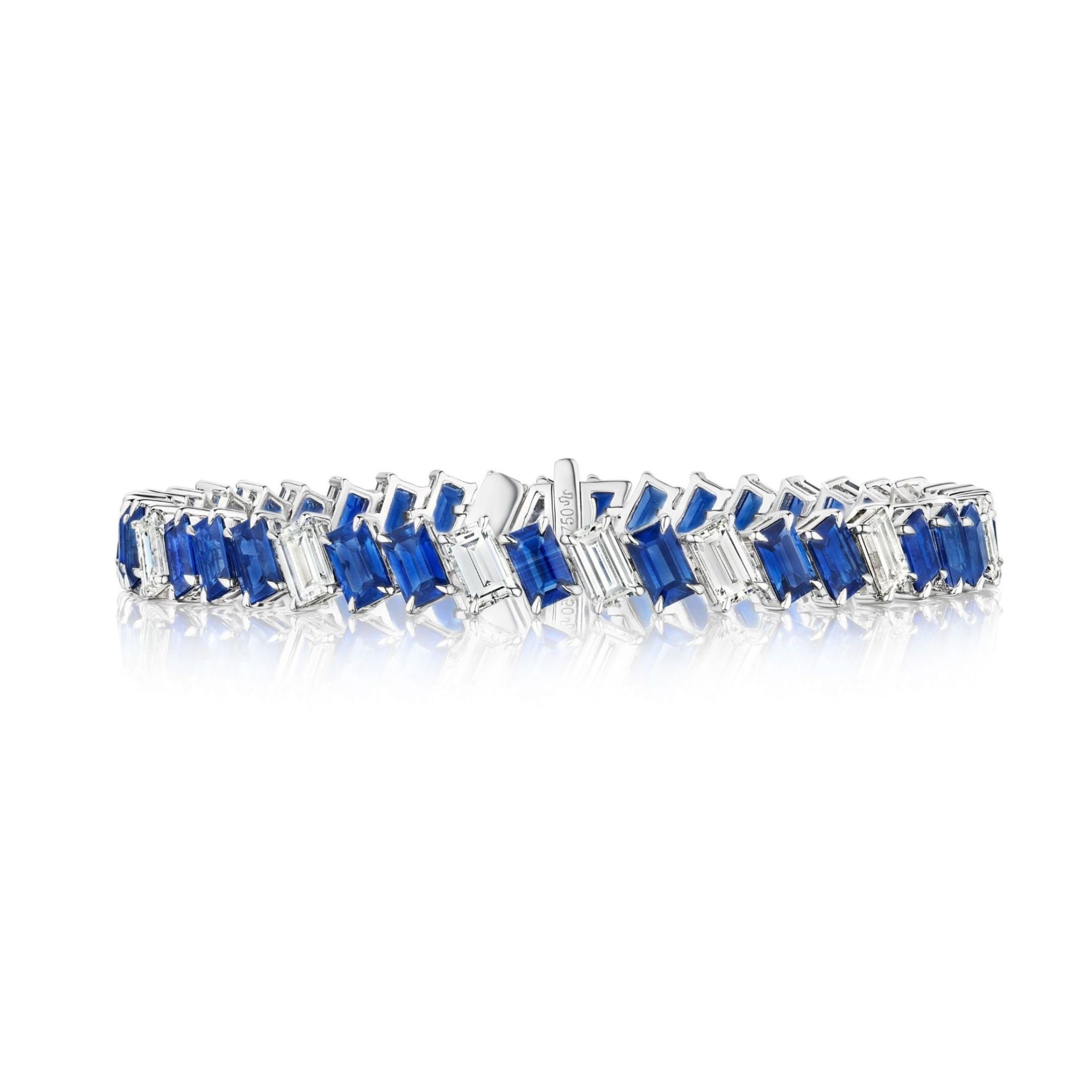 The Chroma Empire Diagonally Set Emerald Cut Sapphire and Diamond Tennis Bracelet displays alternating rectangular blue sapphires and clear diamonds in a zigzag pattern, set in silver, shown on a white background with a subtle reflection.