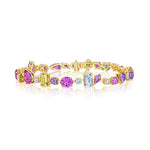 The Chroma Kaleidoscope Mixed Shape Sapphire Tennis Bracelet in yellow gold features vibrant pink, purple, yellow, and blue sapphires in various shapes from the Serpentine Chroma Collection, shown on a white background.