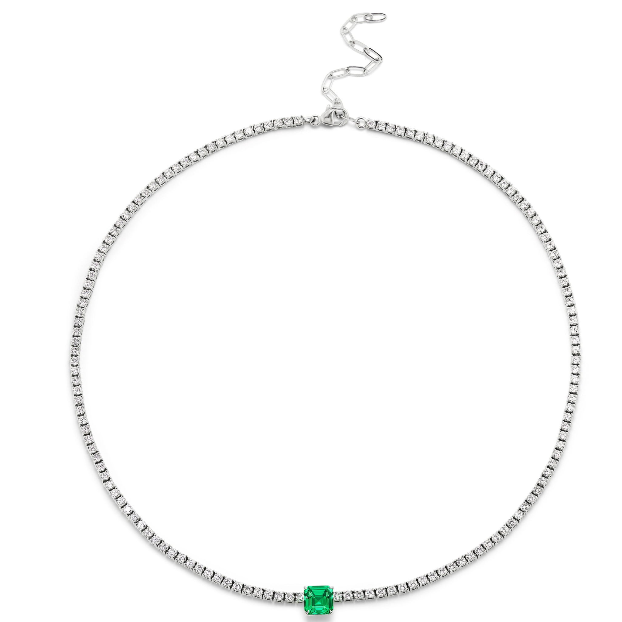 The Classic Tennis Necklace features an Asscher Cut emerald centerpiece in white gold, accented by evenly spaced white stones and finished with an adjustable clasp.