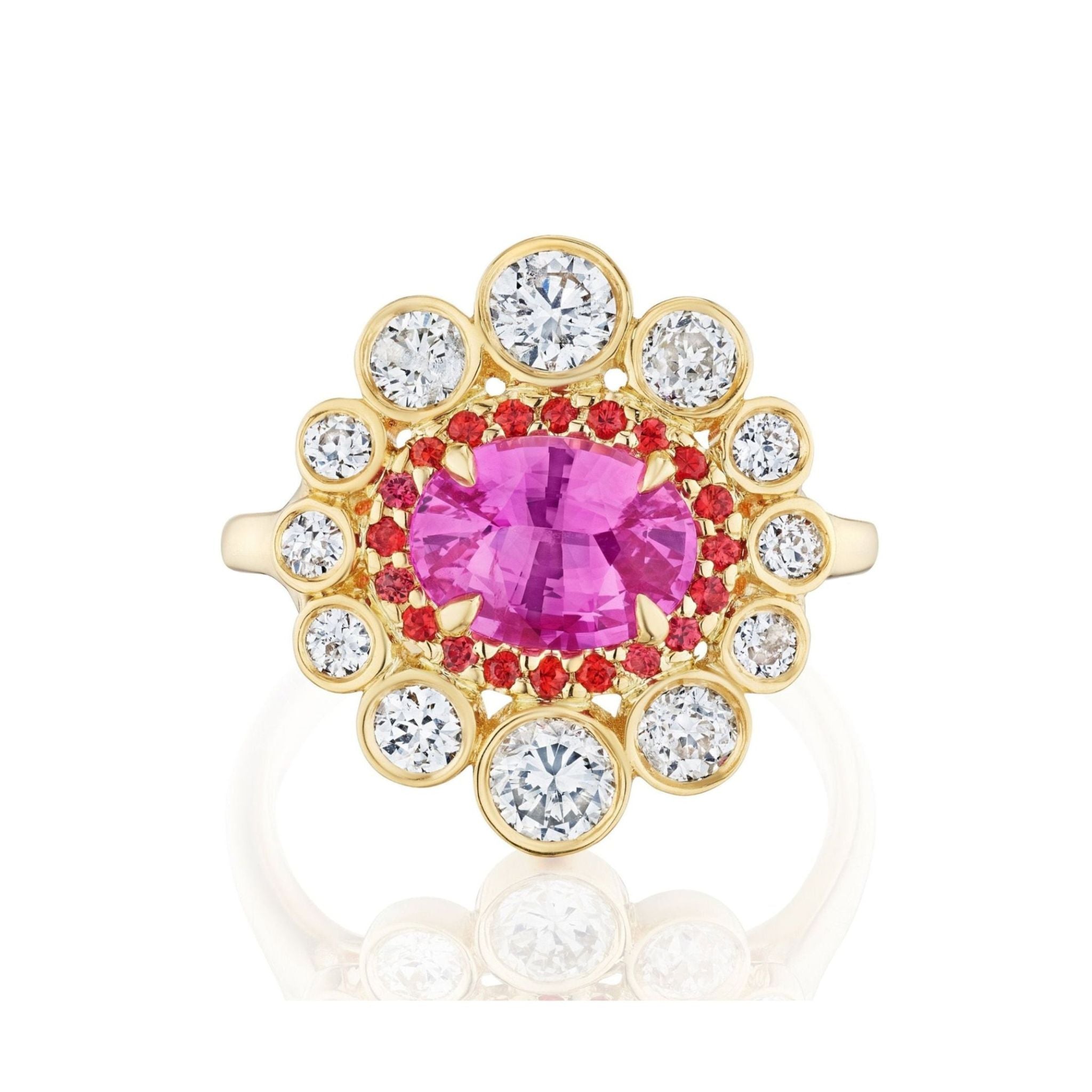 The Cocktail Ring in Yellow Gold features an east-west set oval pink sapphire center, encircled by small red stones and a halo of round white diamonds.