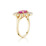 The Cocktail Ring in Yellow Gold features an east-west set oval pink sapphire at the center, surrounded by round diamonds in a floral halo design, shown from a side angle on a plain white background.