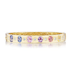 A Burnish Set Multicolor, Mixed Shape, Diamond and Sapphire Bangle in Yellow Gold featuring oval-cut pastel gemstones and round diamonds arranged in a repeating pattern with sparkling oval-cut sapphires, displayed on a white background.