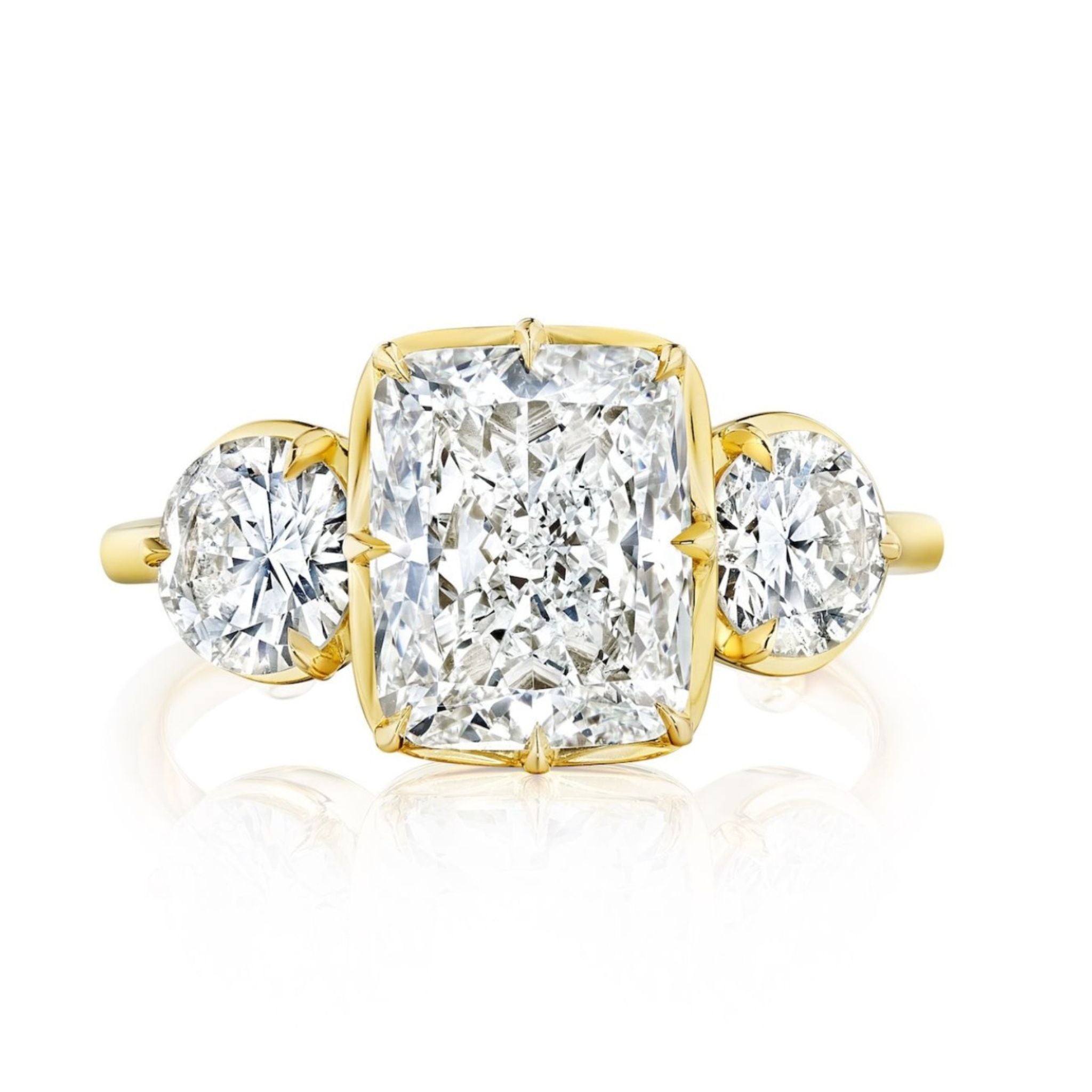 The Collet Set Cushion Cut Diamond Engagement Ring with Round Side Stones in Yellow Gold features a central cushion cut diamond and round side stones, elegantly set against a white background.