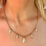 A close-up of a woman wearing the Disco Necklace in Yellow Gold, featuring five step cut pear diamonds evenly spaced along the chain.