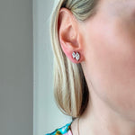 A woman's ear, her light blonde hair tucked back, displays the Duo Studs in White Gold with Marquise Diamonds as part of her face and neck are revealed.