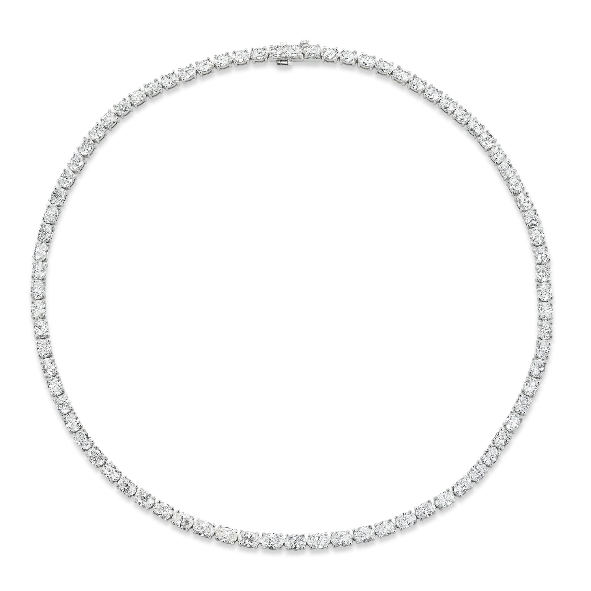 The East-West Oval Diamond Tennis Necklace in White Gold showcases a single row of closely set round diamonds forming an elegant oval shape against a white gold setting.