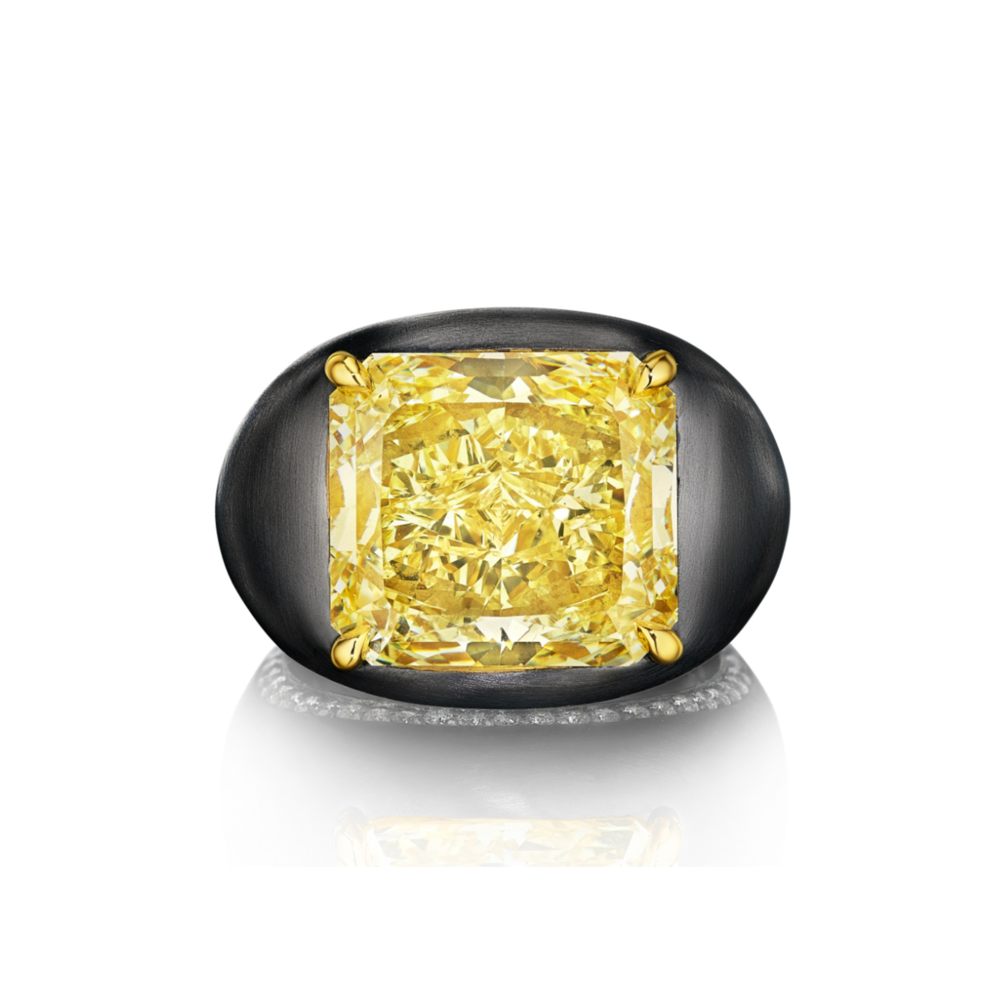The East-West Prong Set Radiant Cut Yellow Diamond Signet Ring in Black Rhodium features a yellow diamond with gold prongs and diamond pavé, showcased on a reflective white surface.