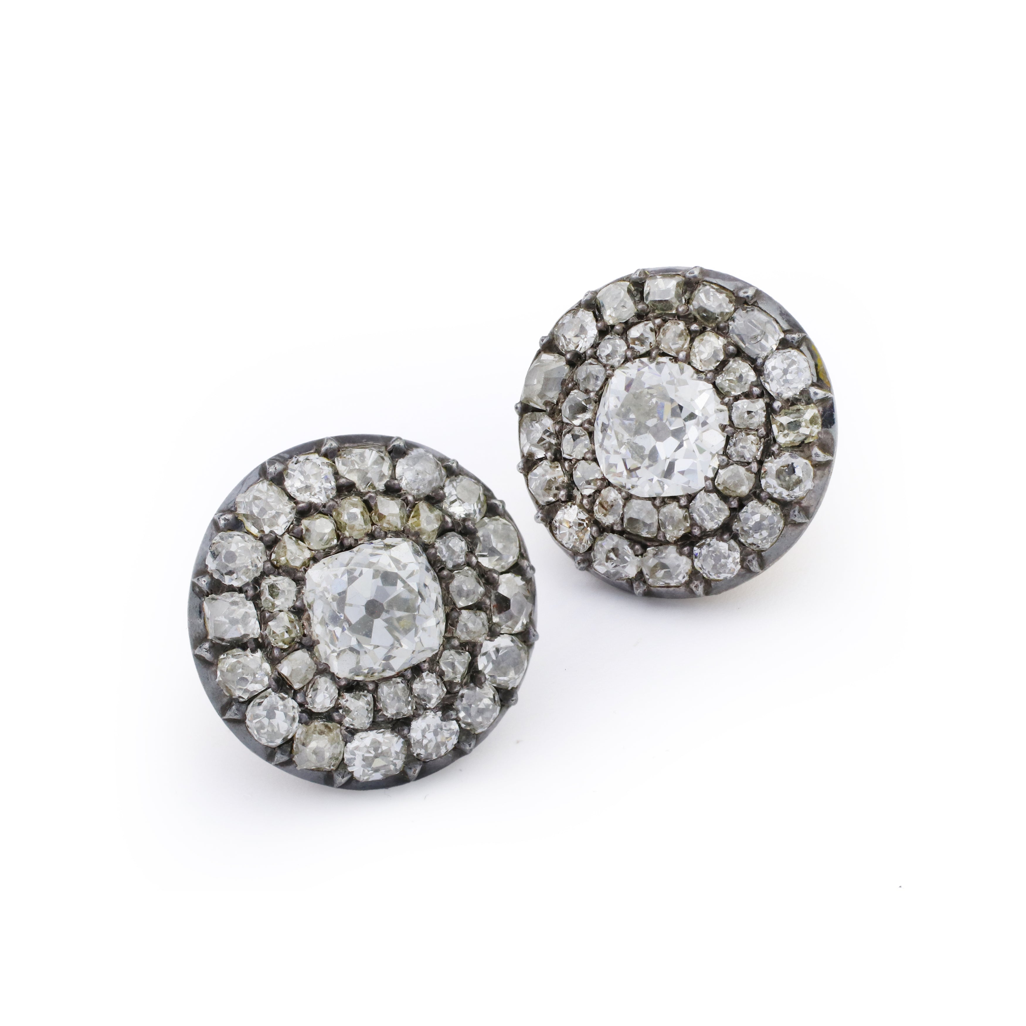 Introducing the Diamond Cluster Earrings, circa 1890: a stunning pair of round vintage earrings showcasing a prominent old mine-cut diamond at the center, encircled by two rows of smaller diamonds in an eye-catching cluster arrangement, all set in dark metal—an exquisite example of antique jewelry.