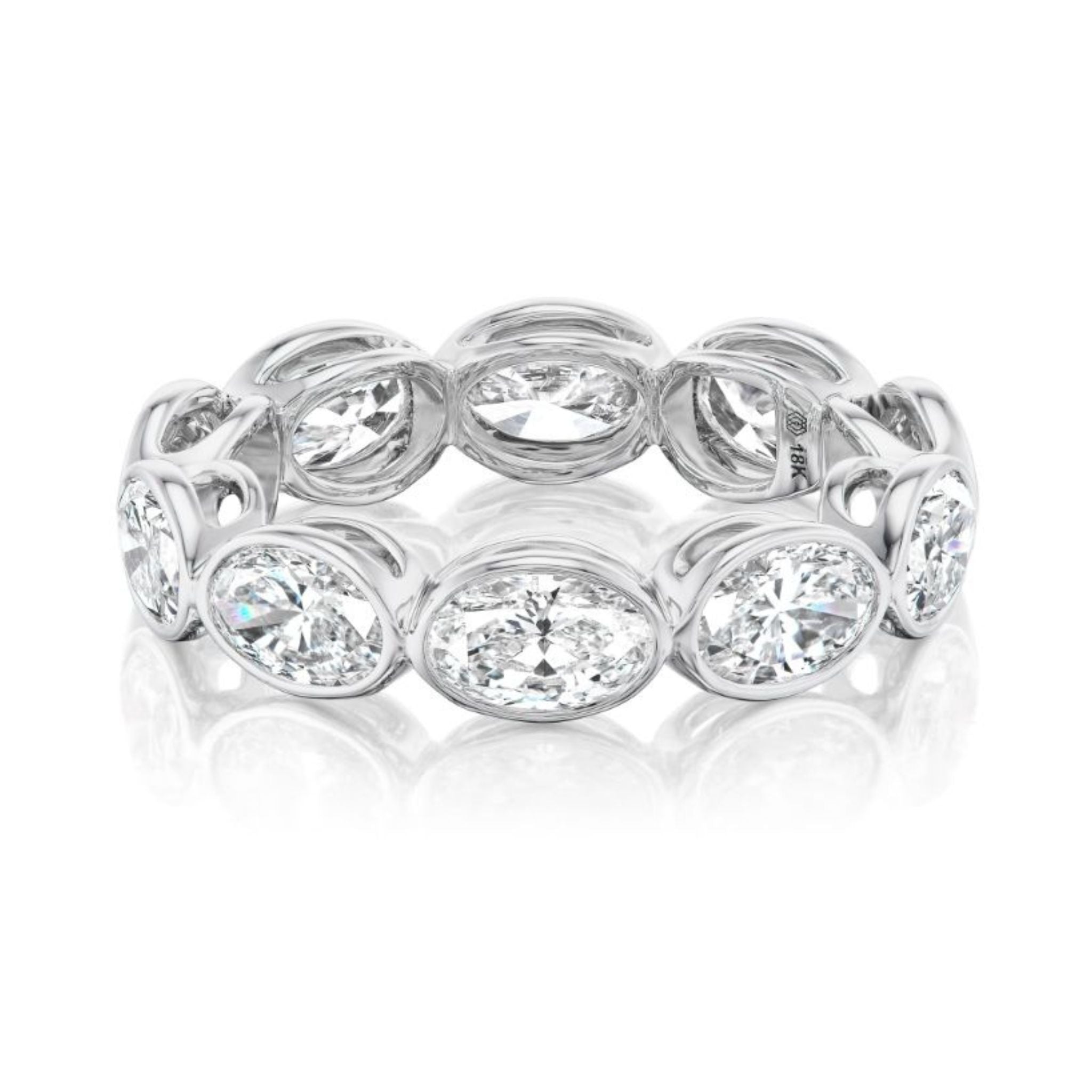 The East-West Bezel Set Oval Diamond Eternity Band in White Gold features oval-cut diamonds in individual bezel settings, creating a continuous circle of brilliance—an ideal addition to any bridal ring collection.