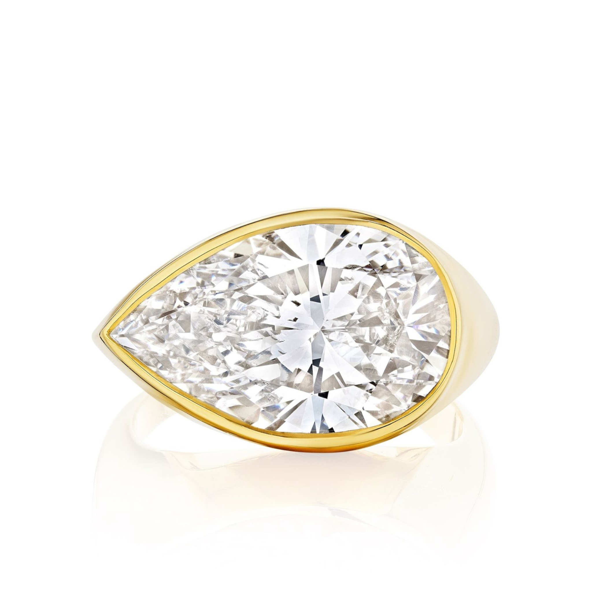The East-West Bezel Set Pear Shape Diamond Ring in Yellow Gold is showcased against a white background, highlighting its oversized pear-shaped diamond in a sleek bezel setting.