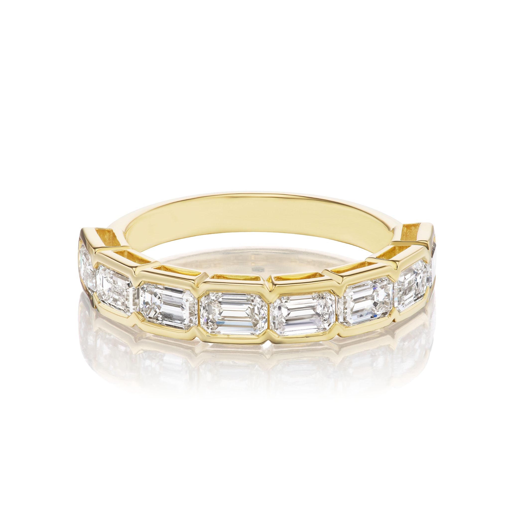 The East-West Bracket Bezel Emerald Cut Diamond Half Eternity Band features a row of emerald cut diamonds set in bezel brackets—perfect for celebration and bridal collections, showcased on a white reflective surface.