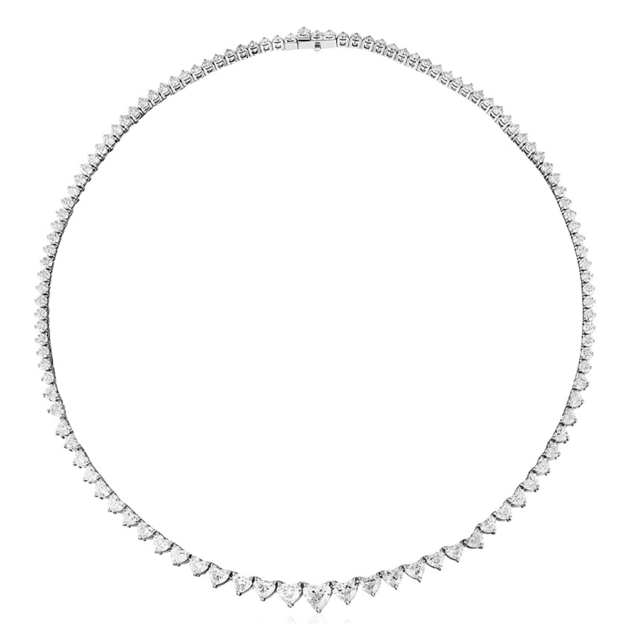 The Graduated Heart Diamond Tennis Necklace in White Gold features a classic design with a single row of diamonds that gradually increase in size toward the center, forming a symmetrical and elegant heart shape. This necklace is made to order in 18K white gold.