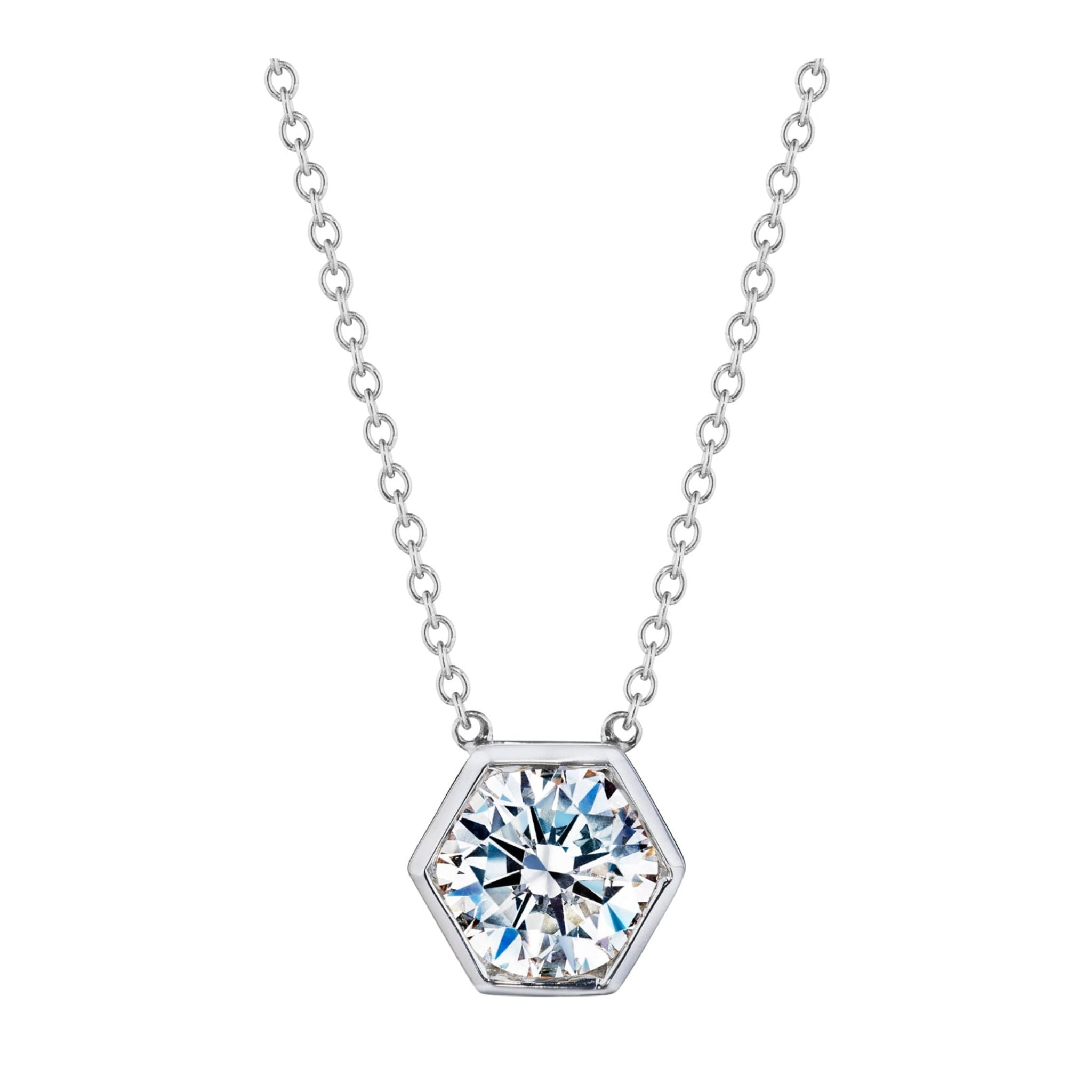 The Hexagon Bezel Set Round Brilliant Diamond Pendant is a silver necklace featuring a hexagon-shaped pendant with a round, bezel set diamond at its center, displayed on a plain white background.
