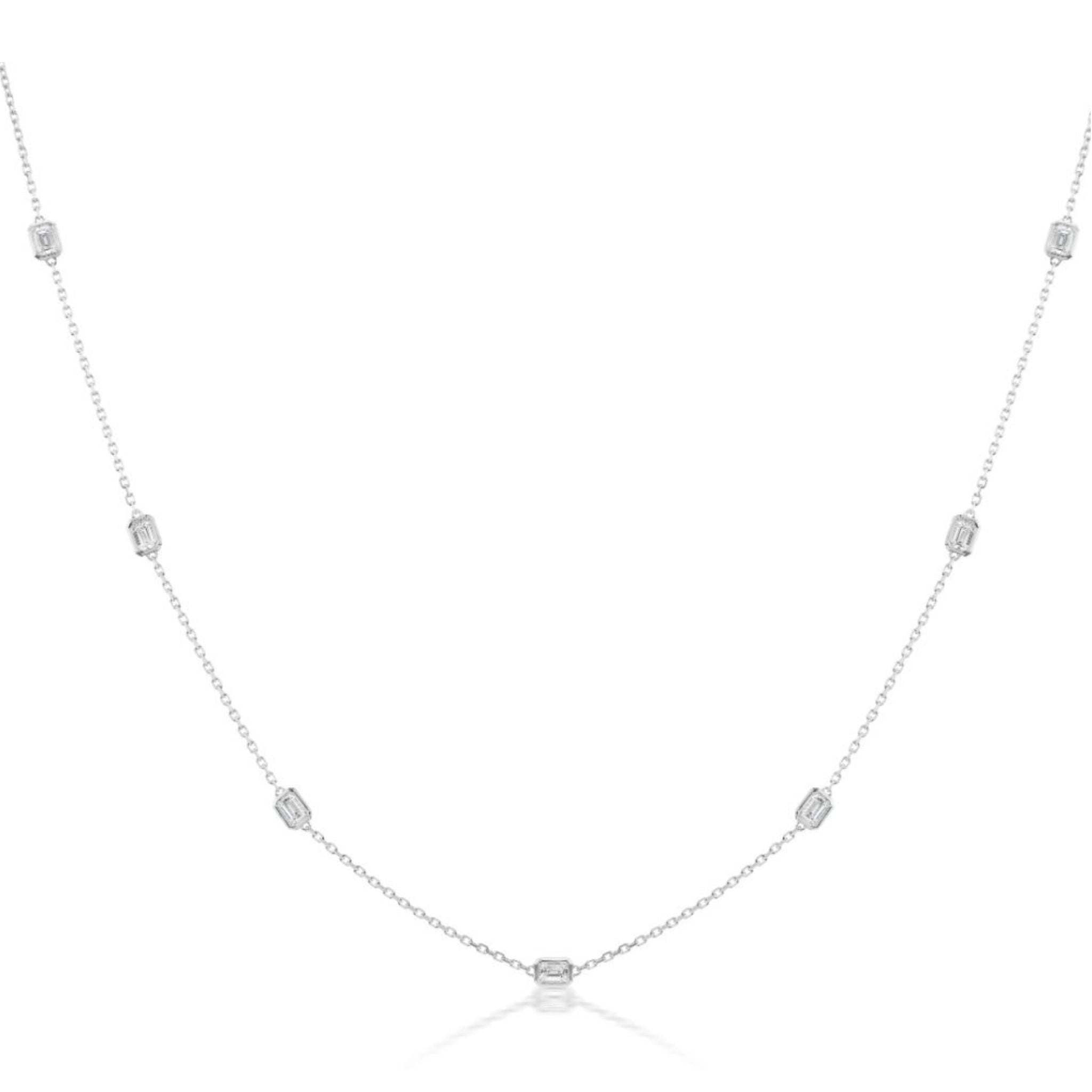 The Serpentine Station Necklace with Emerald Cut Diamonds in White Gold features small emerald cut diamonds, each gemstone delicately spaced along a fine 18K white gold chain, and is displayed on a white background.