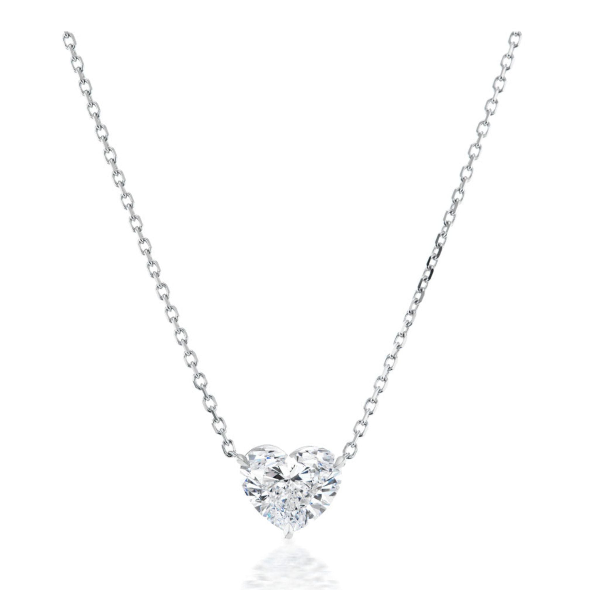 The Heart-Shaped Diamond Solitaire Pendant is showcased on a white background, featuring a delicate silver chain and a center heart-shaped diamond of F color and SI2 clarity.