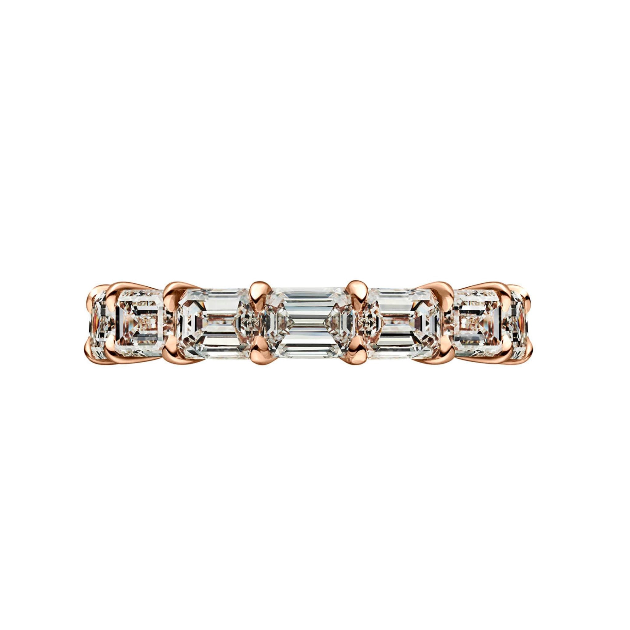 The East-West Emerald Cut Diamond Eternity Band features a row of prong-set rectangular emerald cut diamonds with VVS1+ clarity, each stone reflecting light beautifully against a white background.