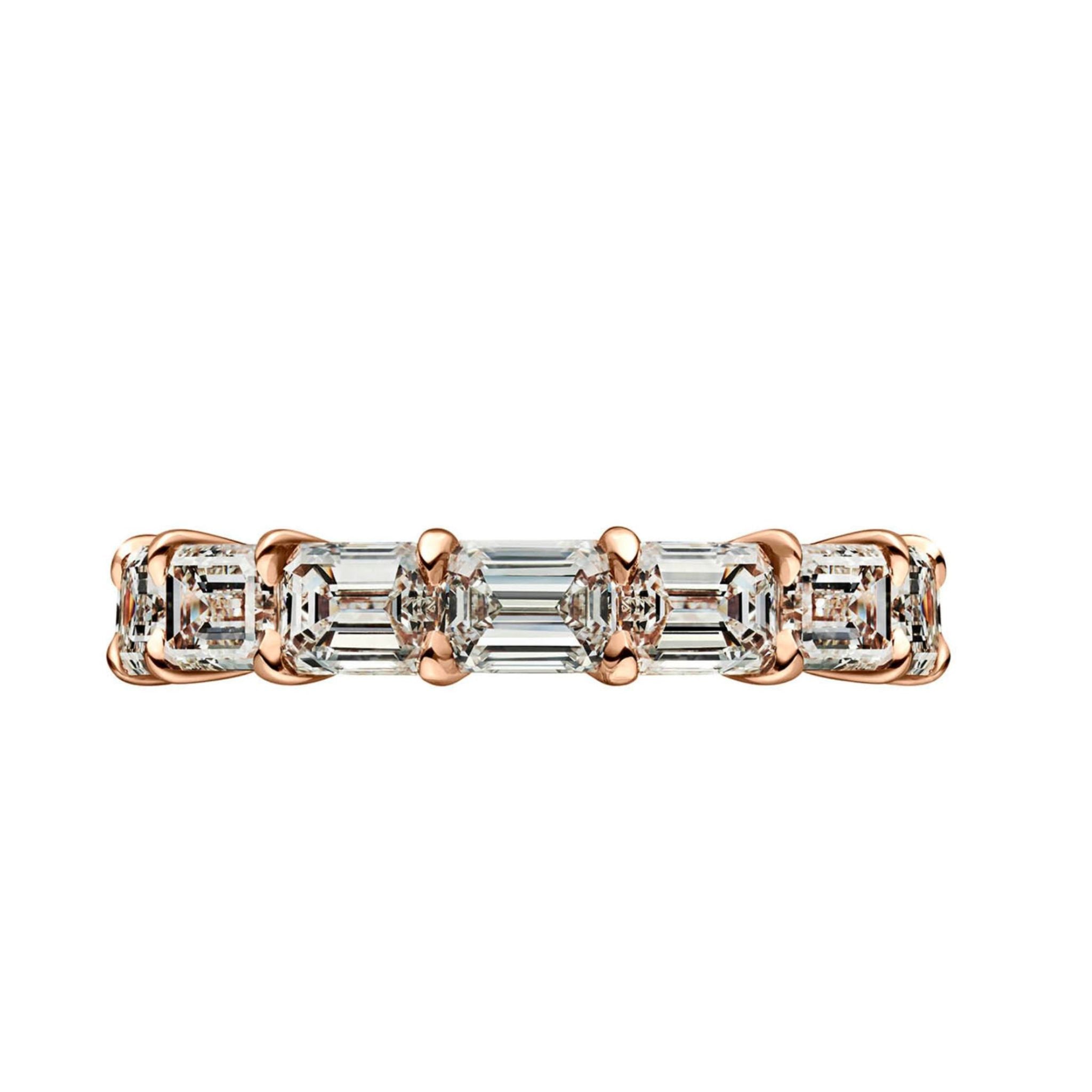 The East-West Emerald Cut Diamond Eternity Band features a sleek gold design with prong-set rectangular emerald cut diamonds, showcasing their brilliance and VVS1 clarity in an elegant, timeless setting.