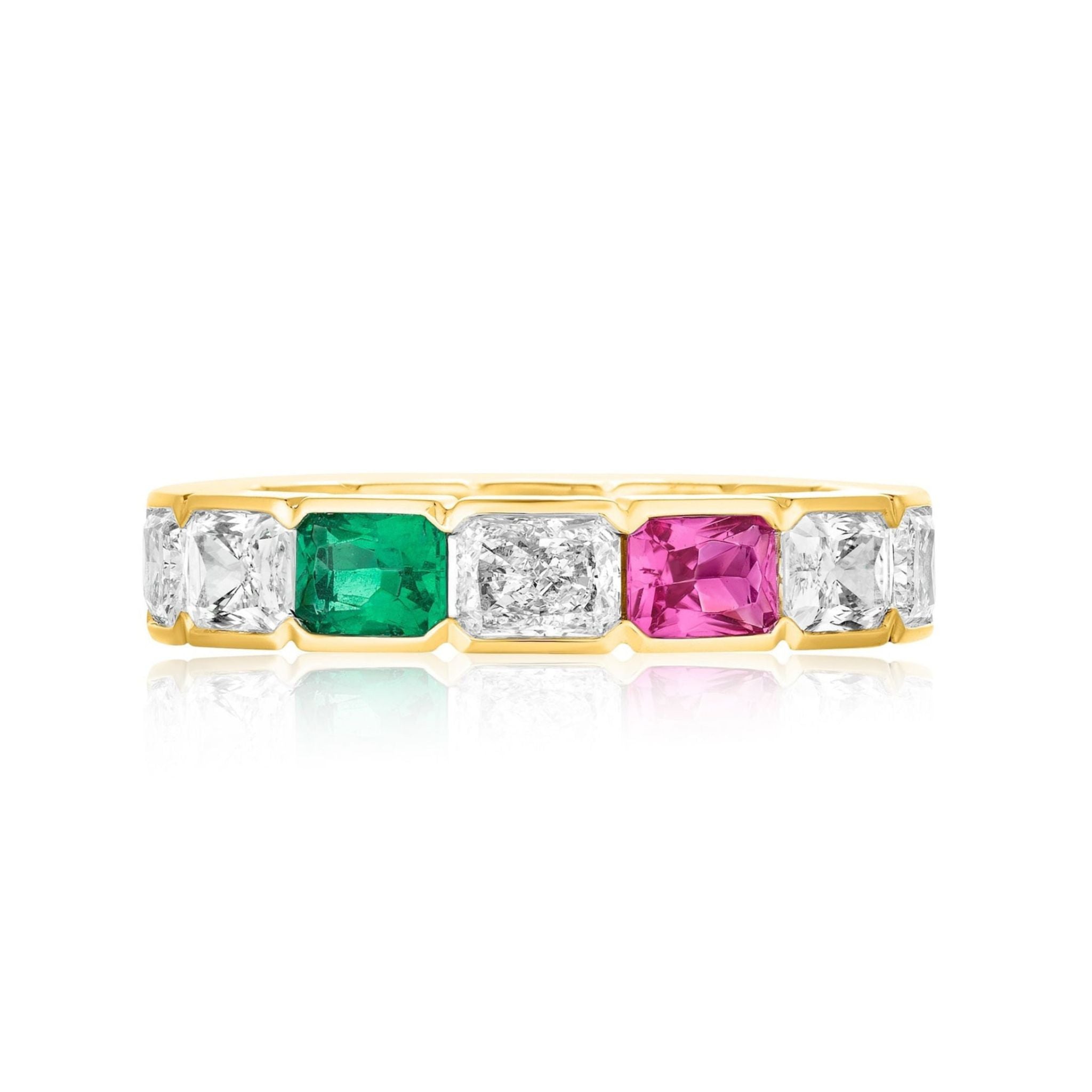 The East-West Half-Bezel Set Radiant Cut Diamond, Emerald, and Sapphire Eternity Band in Yellow Gold features alternating rectangular stones in prong settings, showcased on a white background with a subtle reflection below.