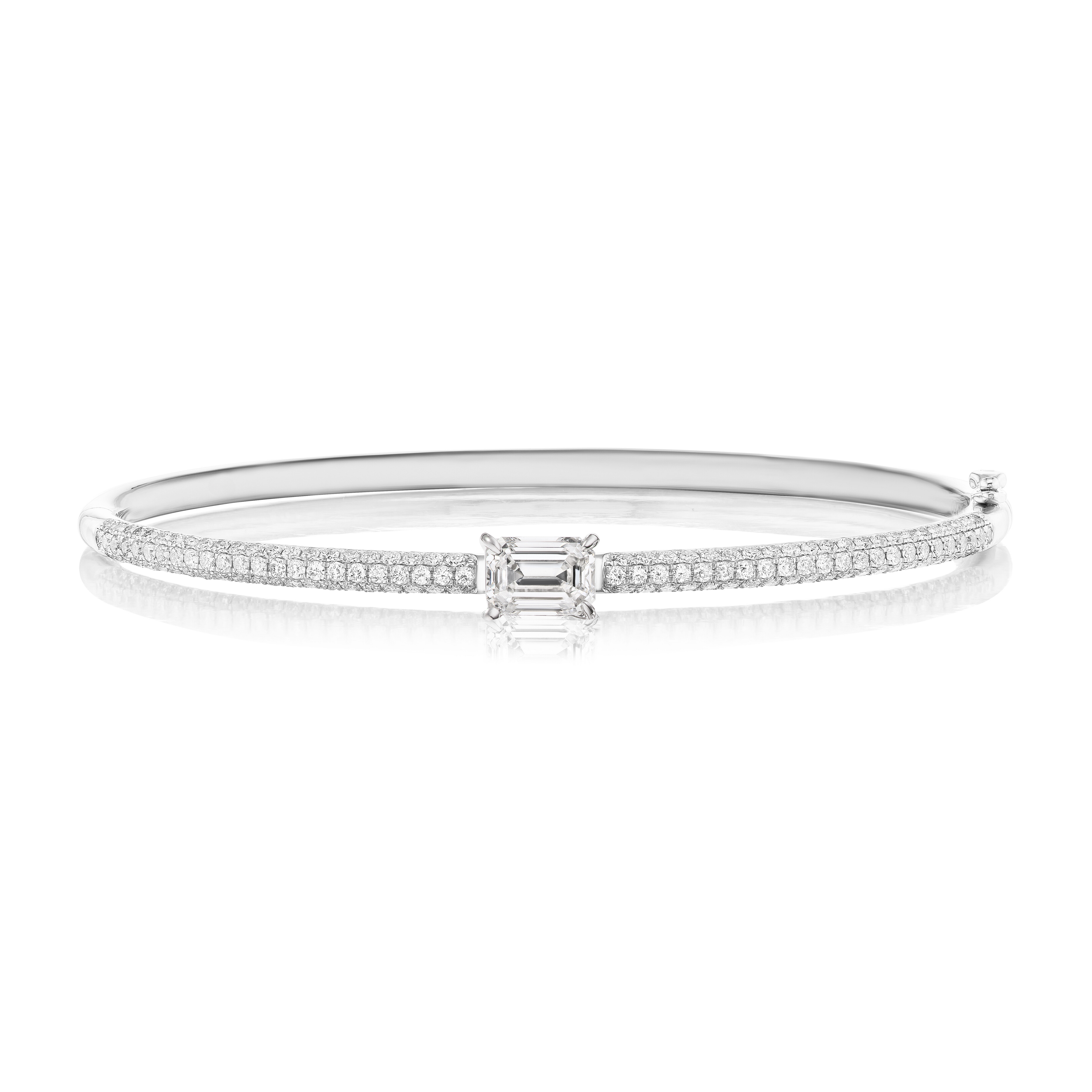 The East-West Set Emerald Cut Diamond Pavé Bangle features an 18k gold band with two rows of pavé diamonds and a striking rectangular emerald-cut diamond centerpiece.