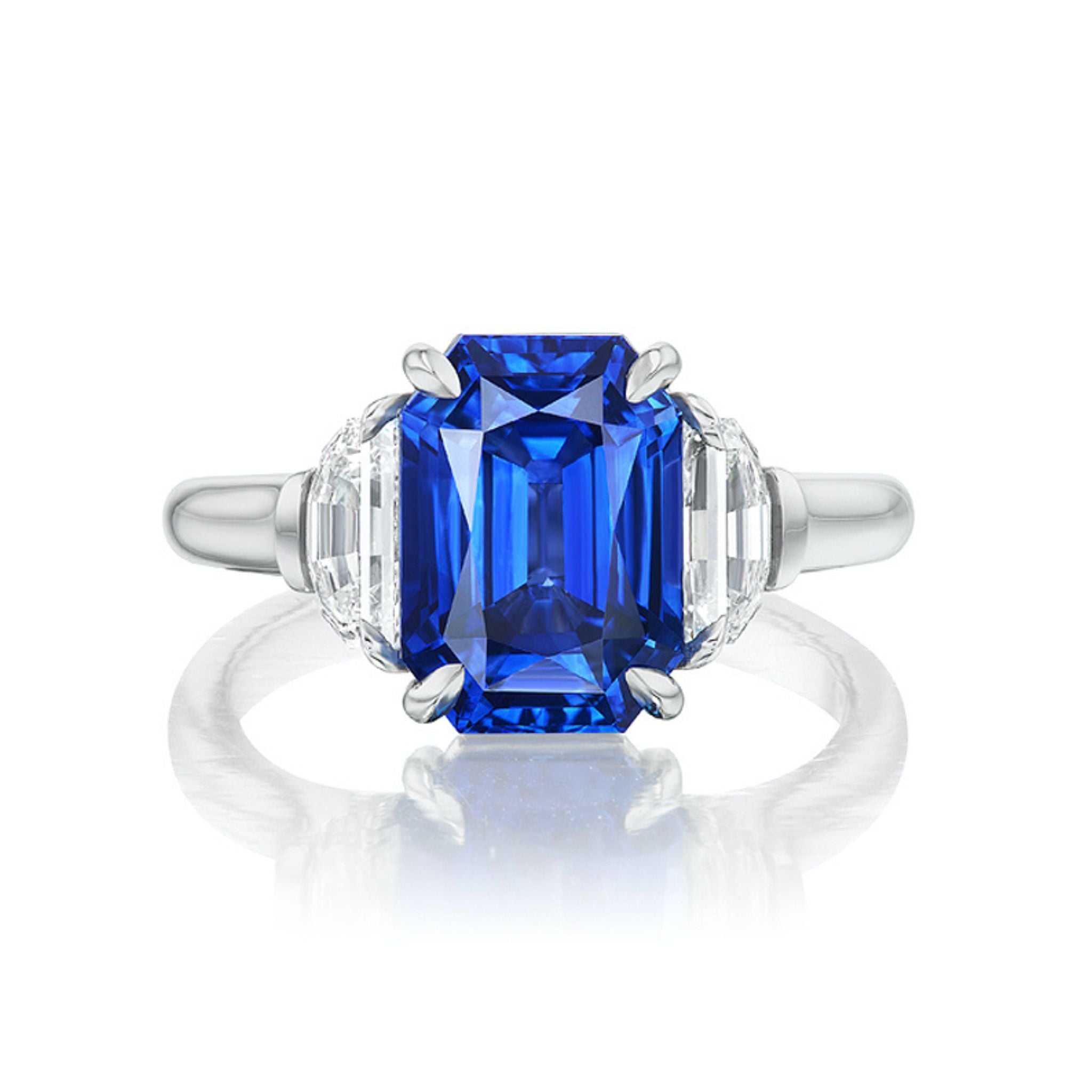 The Emerald Cut Sapphire Engagement Ring with Half Moon Diamond Side Stones features a striking blue center gem and sparkling half-moon diamonds on a polished white gold band—an elegant bridal ring choice.