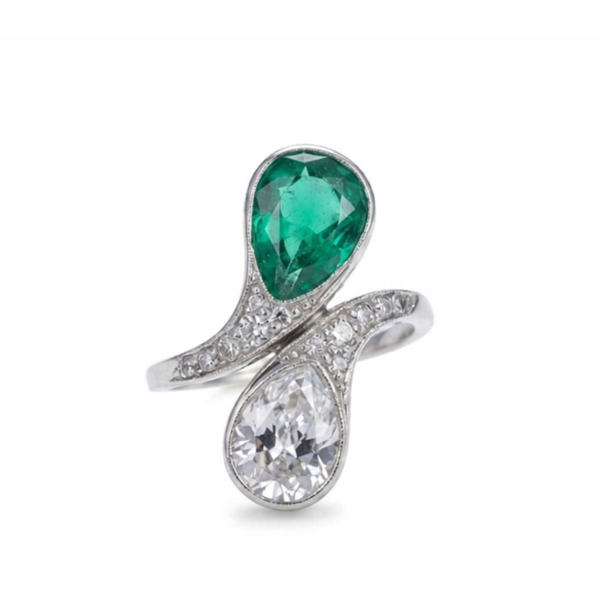 The Emerald and Diamond Bypass Ring is a platinum ring with a pear-shaped green emerald and a pear-shaped diamond set side by side, accented by small round diamonds on the band; comes with an AGL gemstone authenticity report.