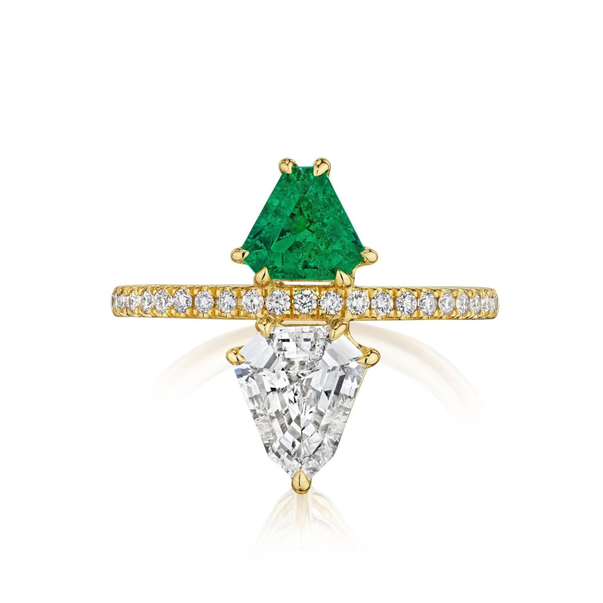 The Emerald and Diamond Double Shield Ring in Yellow Gold showcases a triangular green emerald and a trapezoid white diamond, separated by a yellow gold band adorned with small round diamonds.