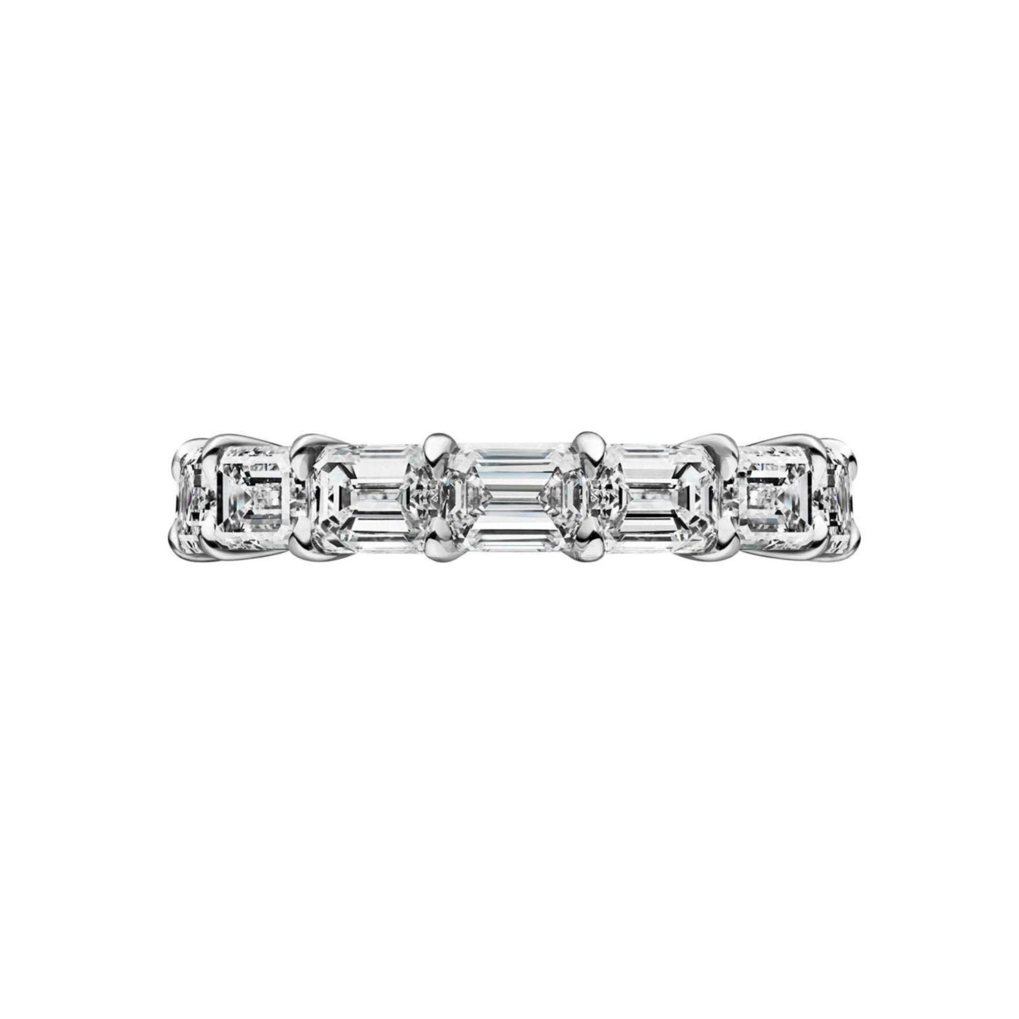 The East-West Emerald Cut Diamond Eternity Band showcases a continuous row of D-E color, VVS1 clarity emerald cut diamonds set in a sleek platinum band, displayed against a plain white background.