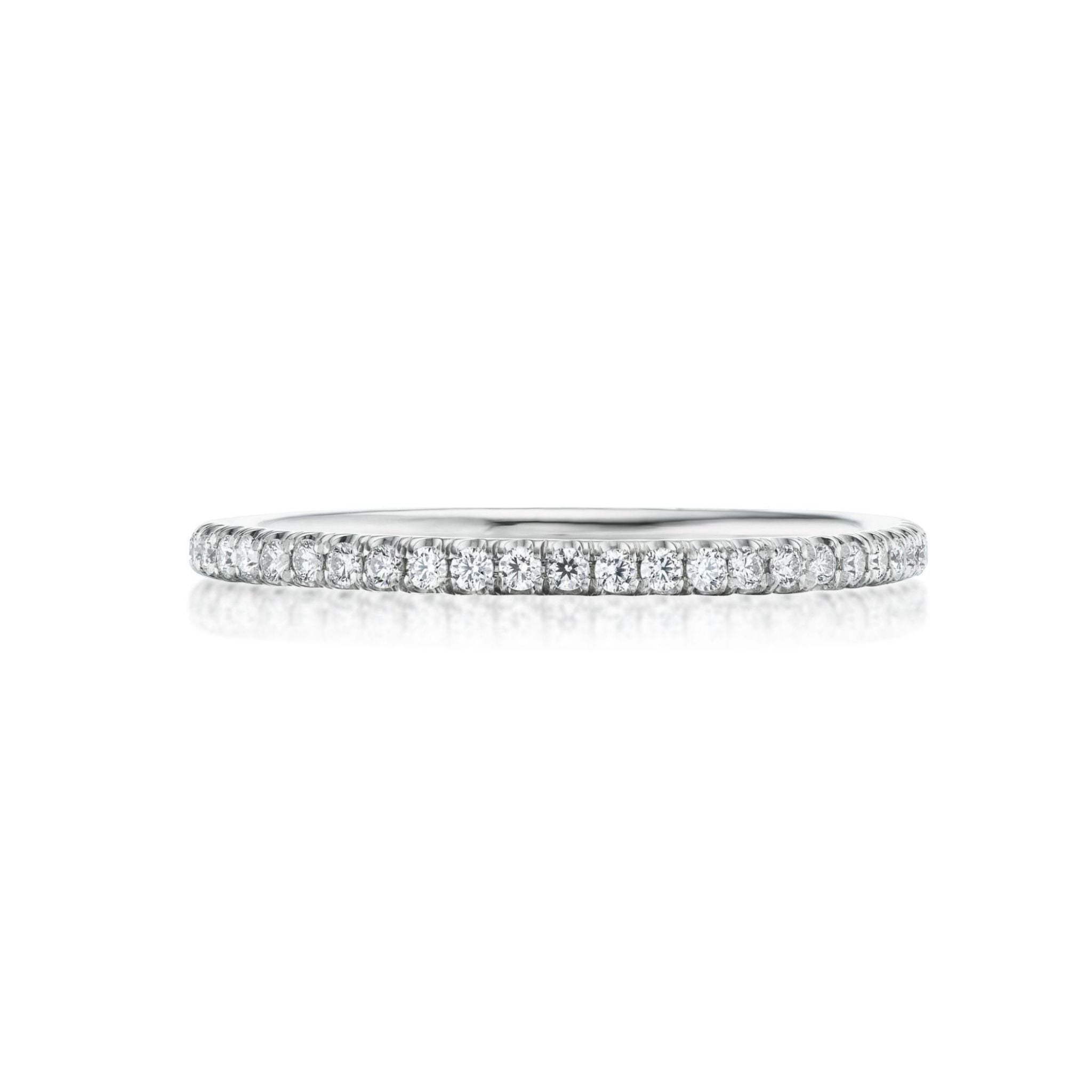 The Round Diamond Eternity Band is a thin ring crafted from 18k white gold, featuring small, round white diamonds set in a continuous row around the band and shown against a white background.