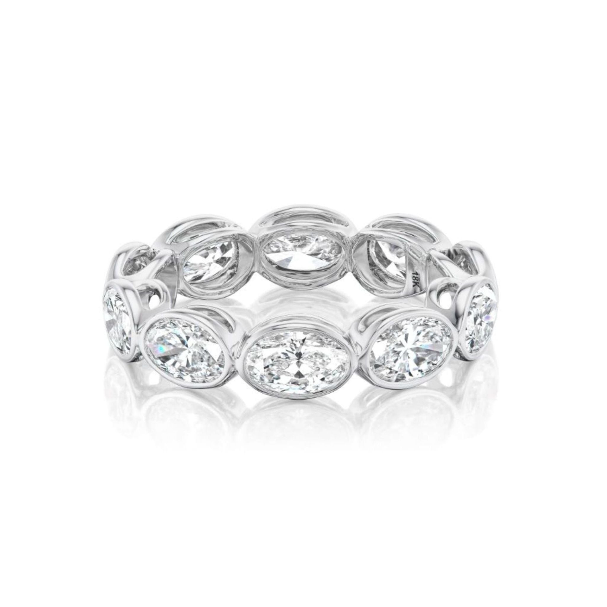 The East-West Bezel Set Oval Diamond Eternity Band in White Gold features oval-cut diamonds set in individual bezels to form a continuous loop. With its polished, reflective surface, this elegant piece is perfect as a celebration ring or an addition to your bridal ring collection and is beautifully displayed against a white background.