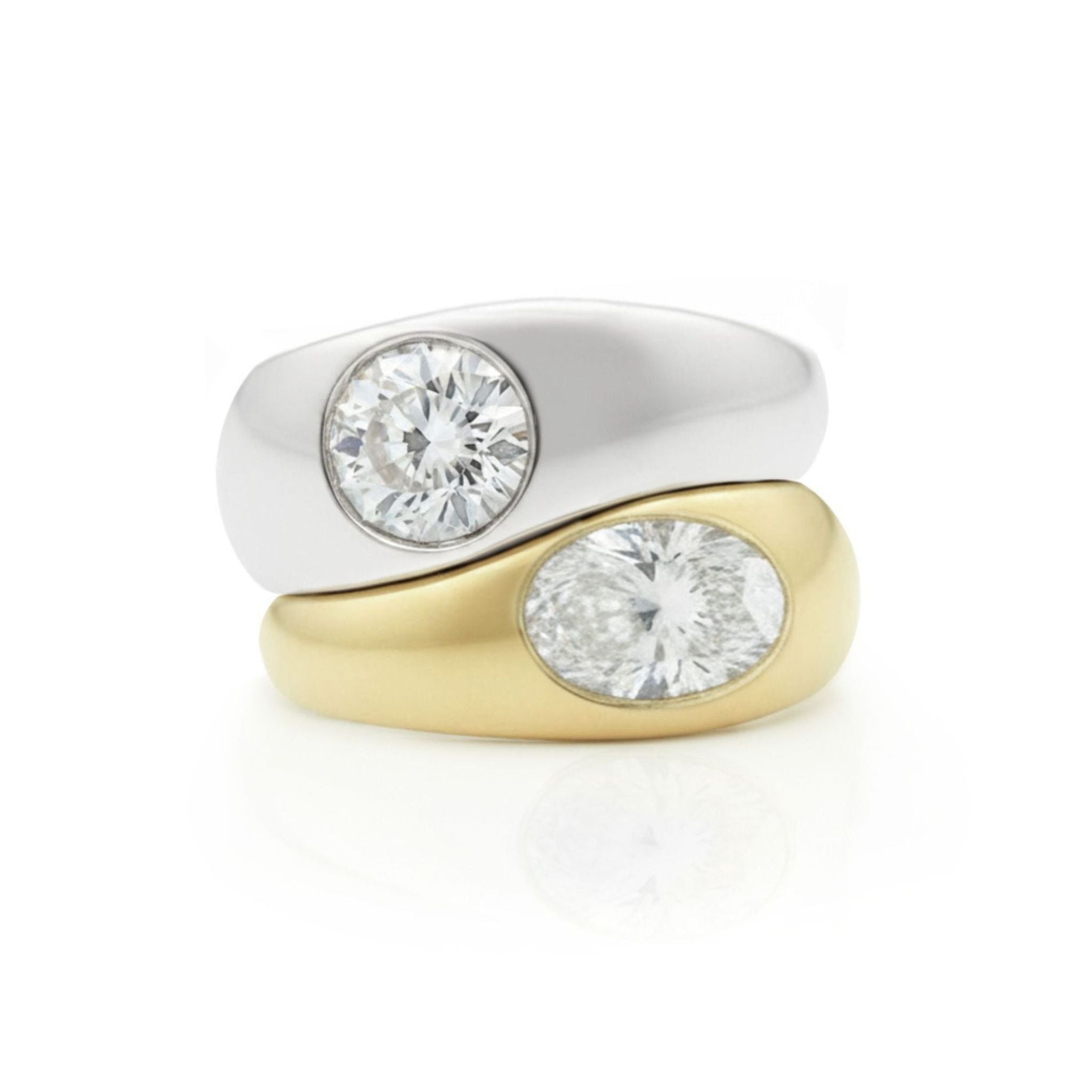 A stacked set featuring the Burnish Set Round Diamond ring in white gold and an oval shape diamond ring in yellow gold, both showcasing a smooth modern design on a white background.