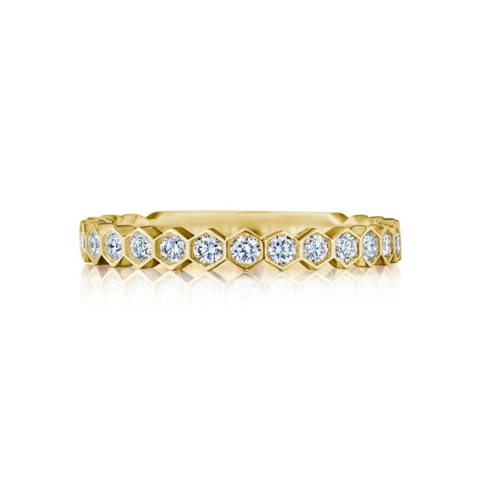 The Hexagon Bezel Set Diamond Band showcases a continuous row of round, bezel-set diamonds accentuated by sleek hexagonal settings in 18k gold, beautifully displayed against a pristine white background.