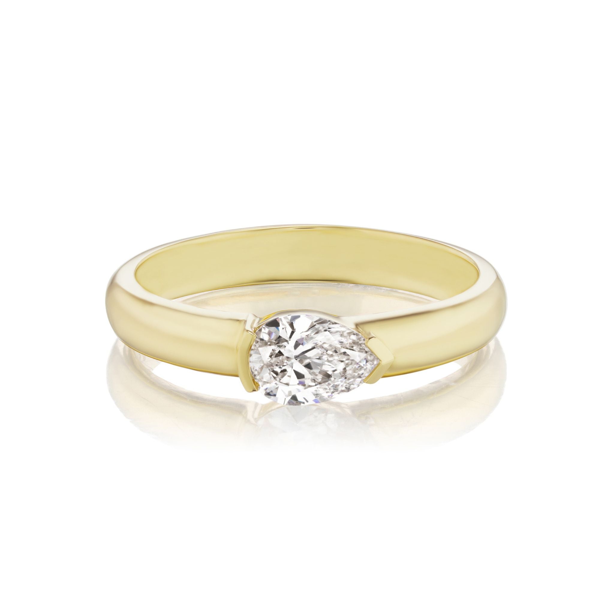 The East-West Pear Diamond Solitaire Band features a single pear-shaped diamond set in an elegant, minimalist 18k gold band. Displayed on a white background with a subtle reflection beneath it, this ring offers customizable sizing for the perfect fit.