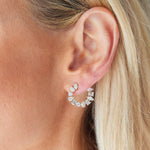 A close-up of a light-skinned person with blonde hair wearing Front-to-Back Hoops with Mixed Shape Diamonds, featuring semi-circular silver hoops adorned with mixed shape diamonds.