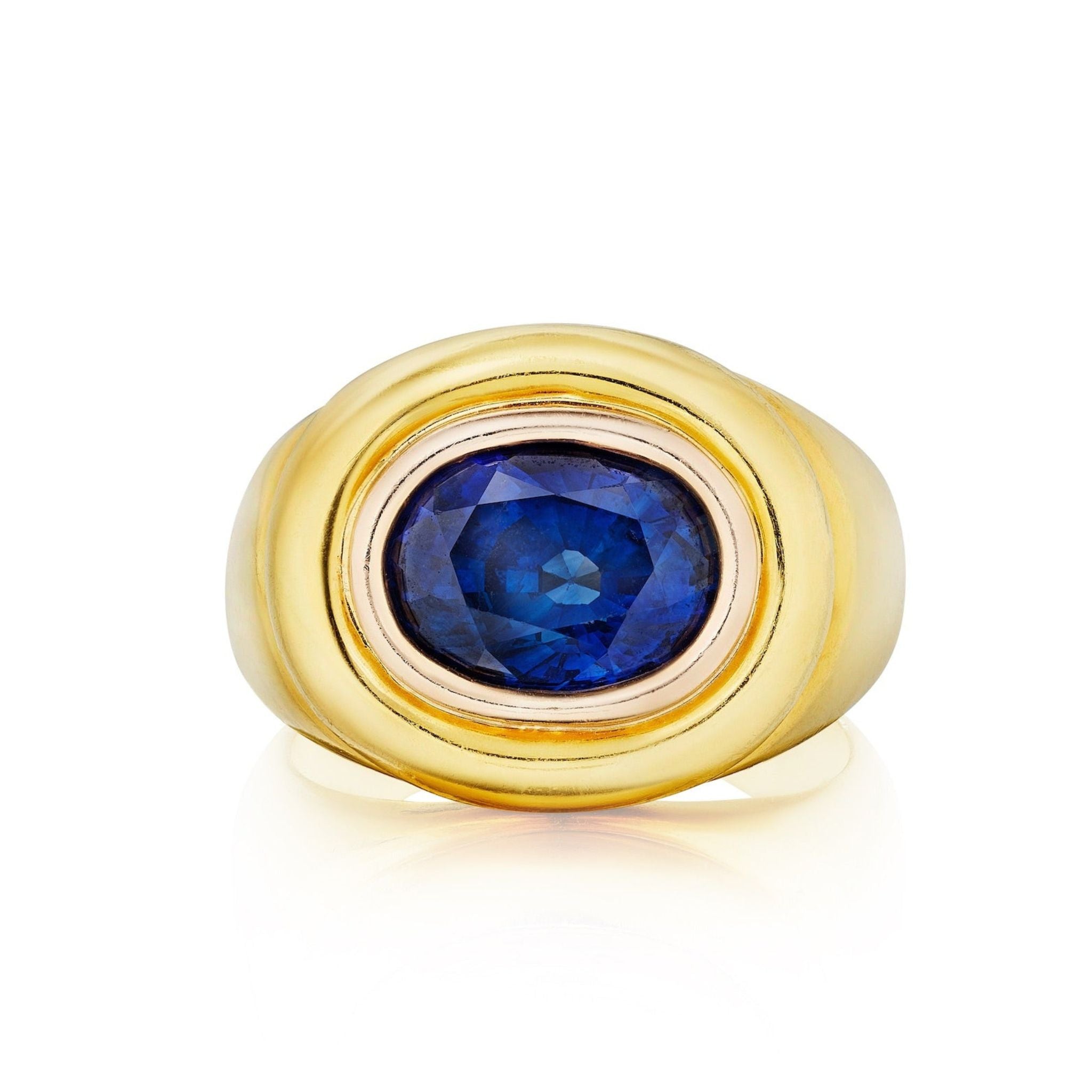 The Gold and Sapphire Ring features a wide gold mounting with an oval blue sapphire at the center, outlined by a thin metallic border, and is displayed against a white background.