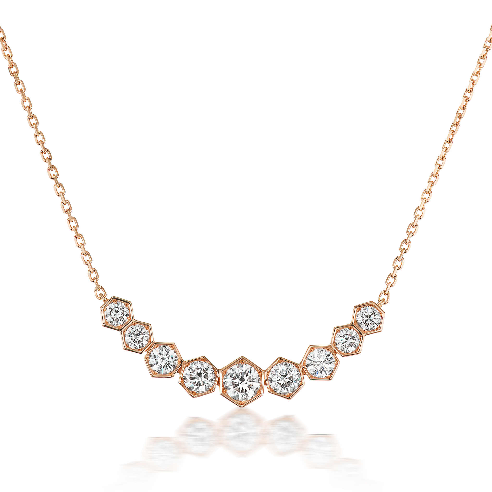 The Graduated Hexagon Necklace with Round Brilliant Diamonds features a row of sparkling round diamonds in hexagonal settings along the center, forming an elegant curve.