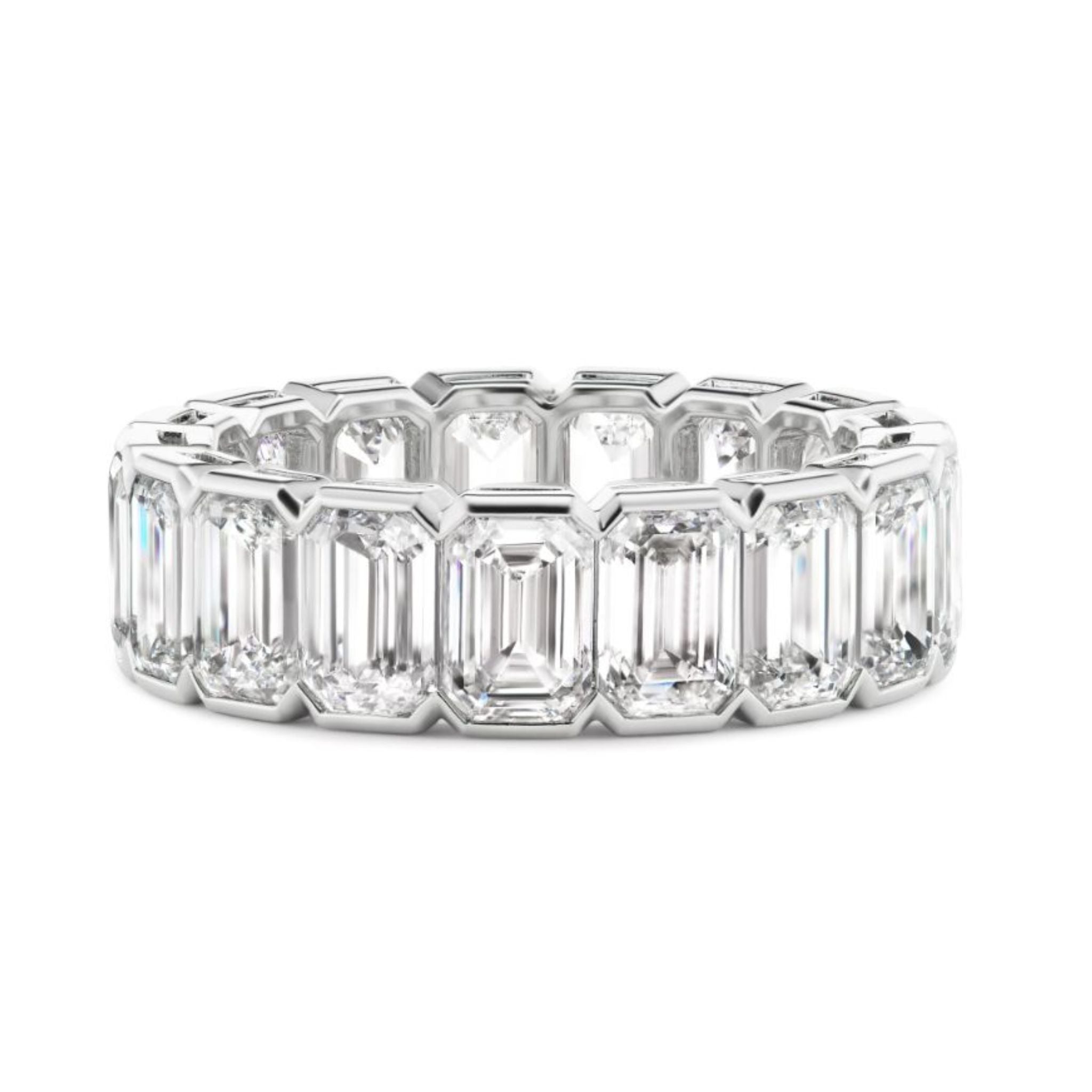 The Half Bezel Emerald Cut Diamond Eternity Band features a continuous row of large emerald-cut diamonds set closely together in platinum, offering an elegant and luxurious design.