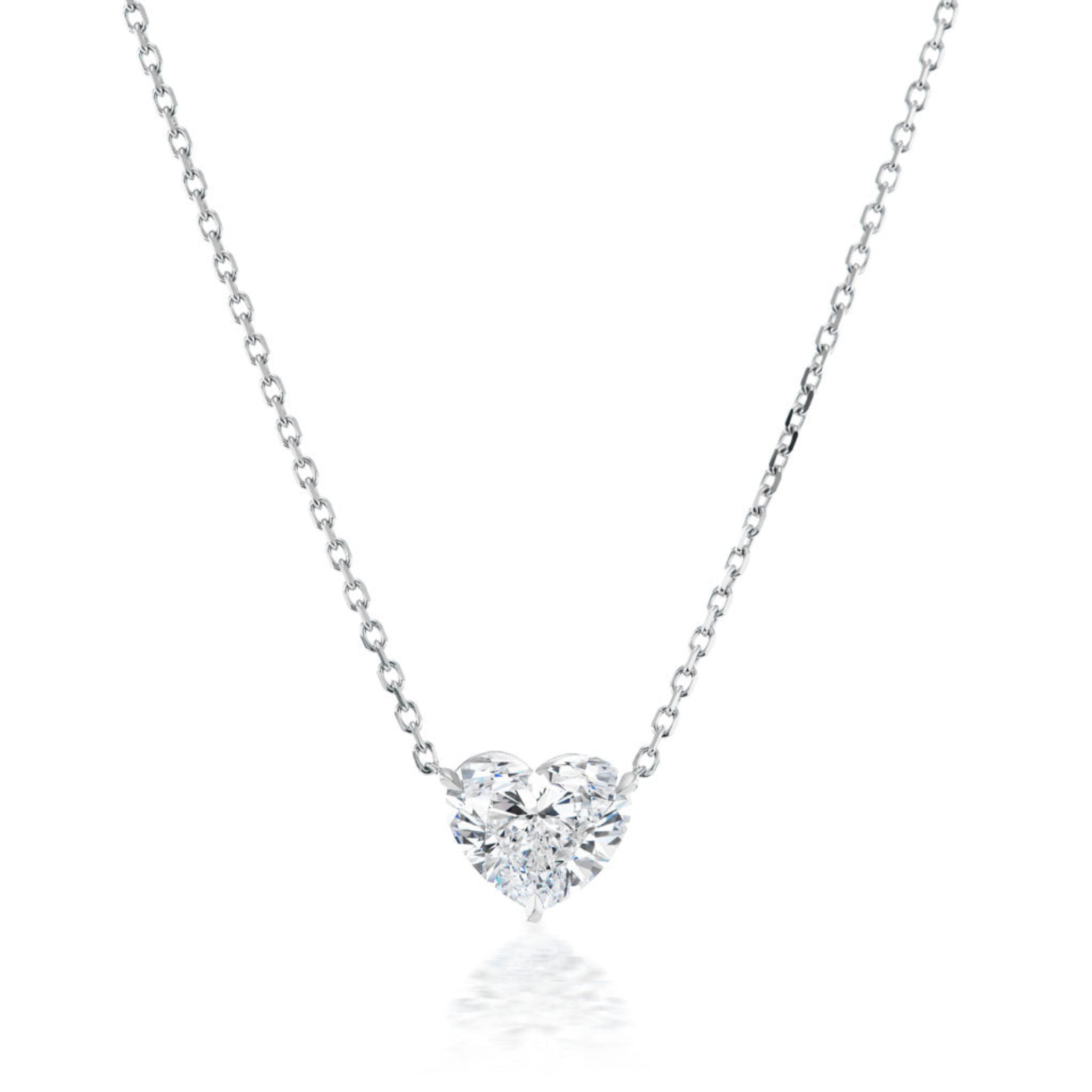 The Heart Diamond Solitaire Pendant is a delicate silver chain necklace with a heart-shaped diamond center, shown on a white background.