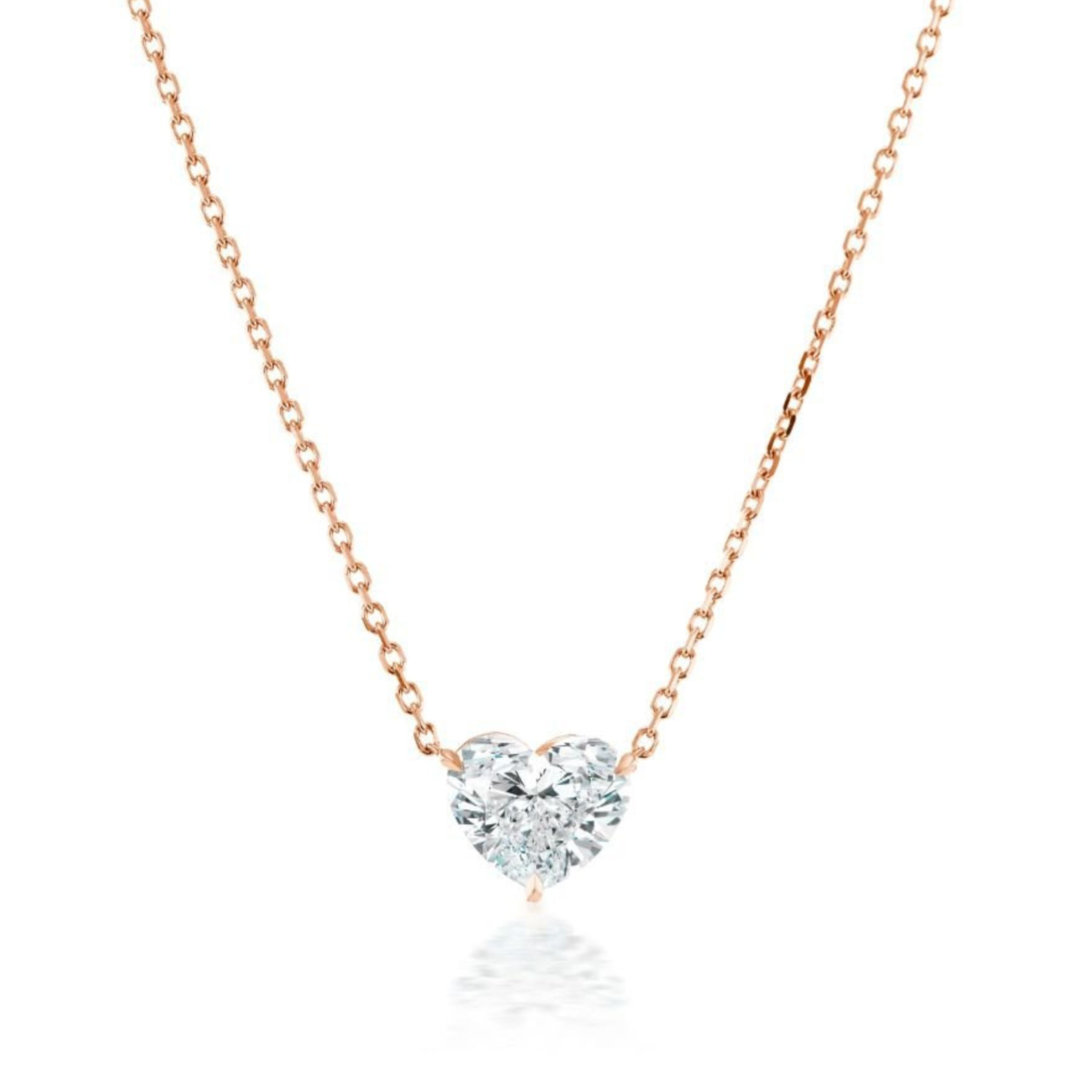 The Heart Diamond Solitaire Pendant in Rose Gold features a sparkling heart-shaped diamond on a delicate 18K rose gold chain, displayed against a white background.