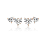 The Duo Studs with Heart Diamonds feature two heart-shaped clear gemstones on each earring, set in 18k white and rose gold prongs, with a larger central heart and a smaller heart beside it.